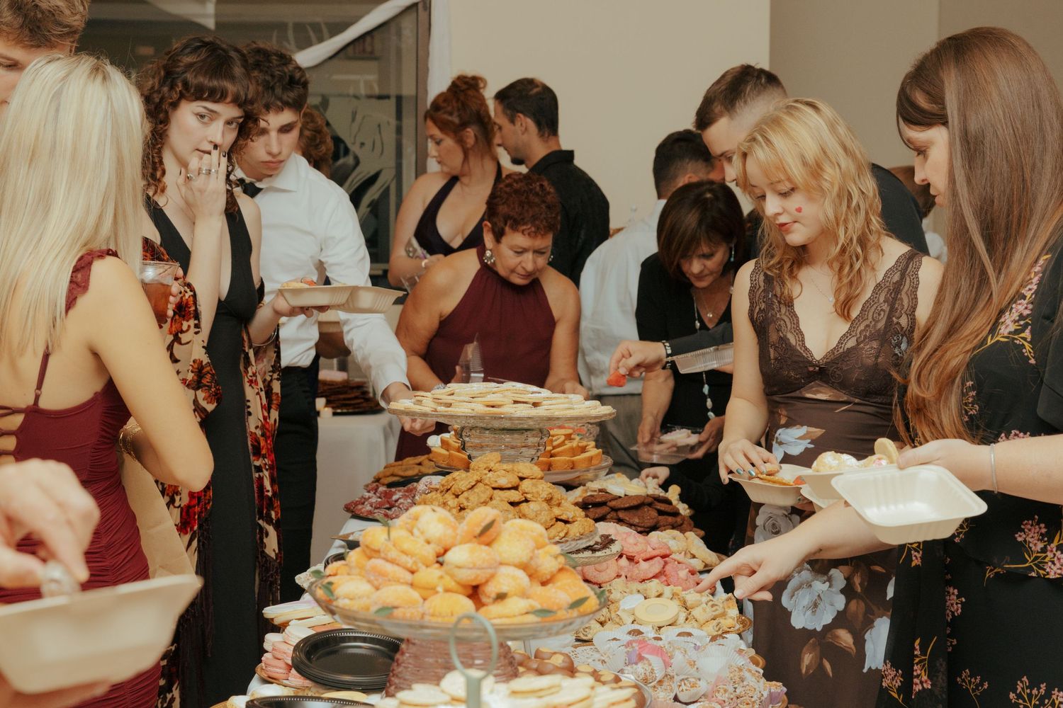 Guests serving themselves at a buffet table filled with assorted foods at a wedding reception.