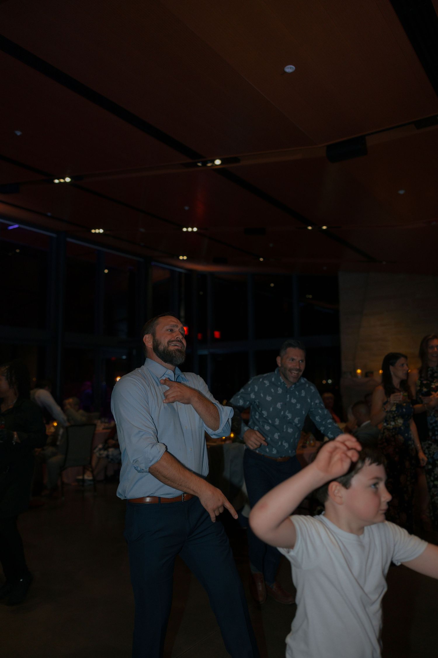 Guests dance energetically on the dance floor during a lively wedding reception celebration.