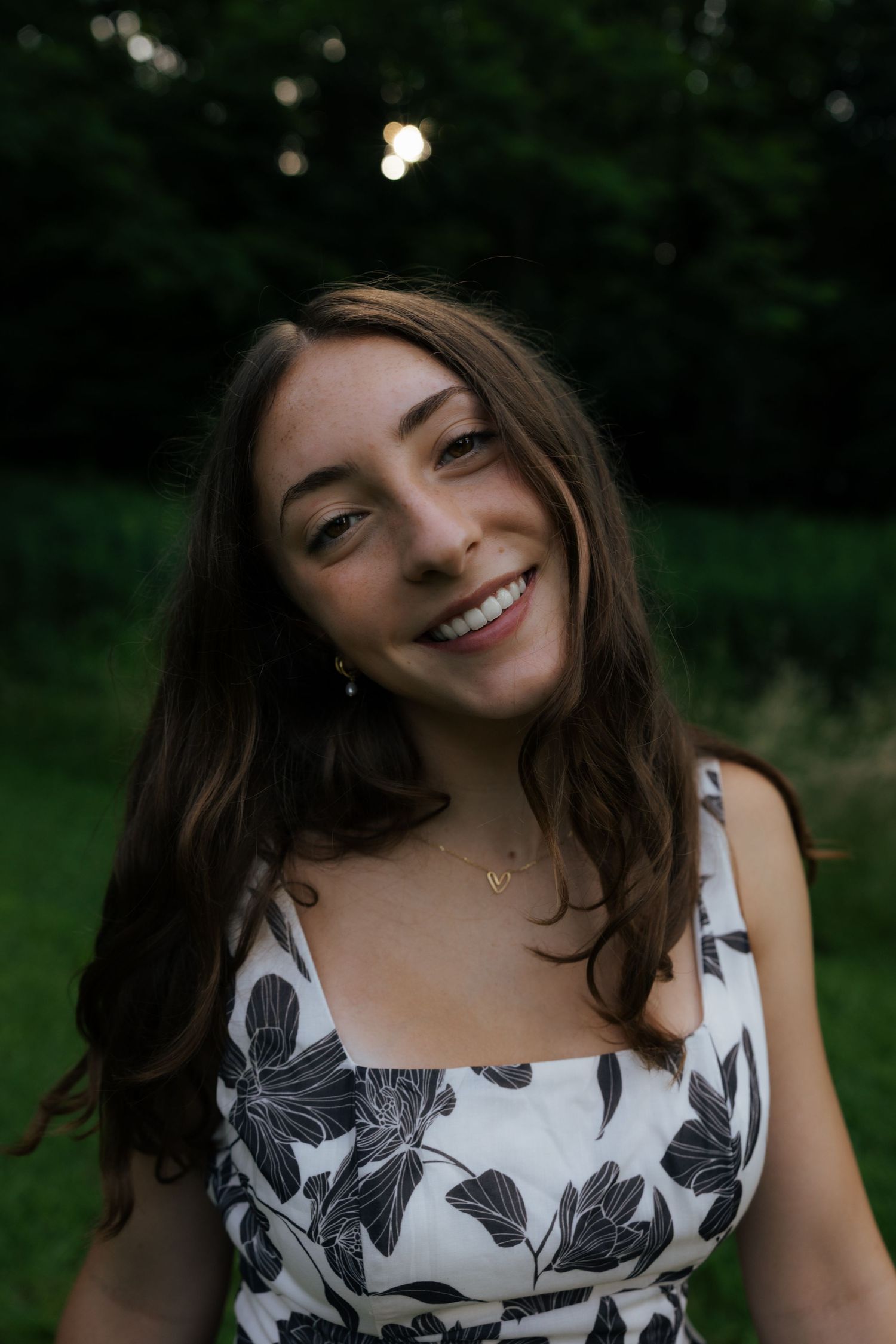 Happy young woman in floral sundress laughing in lush garden.