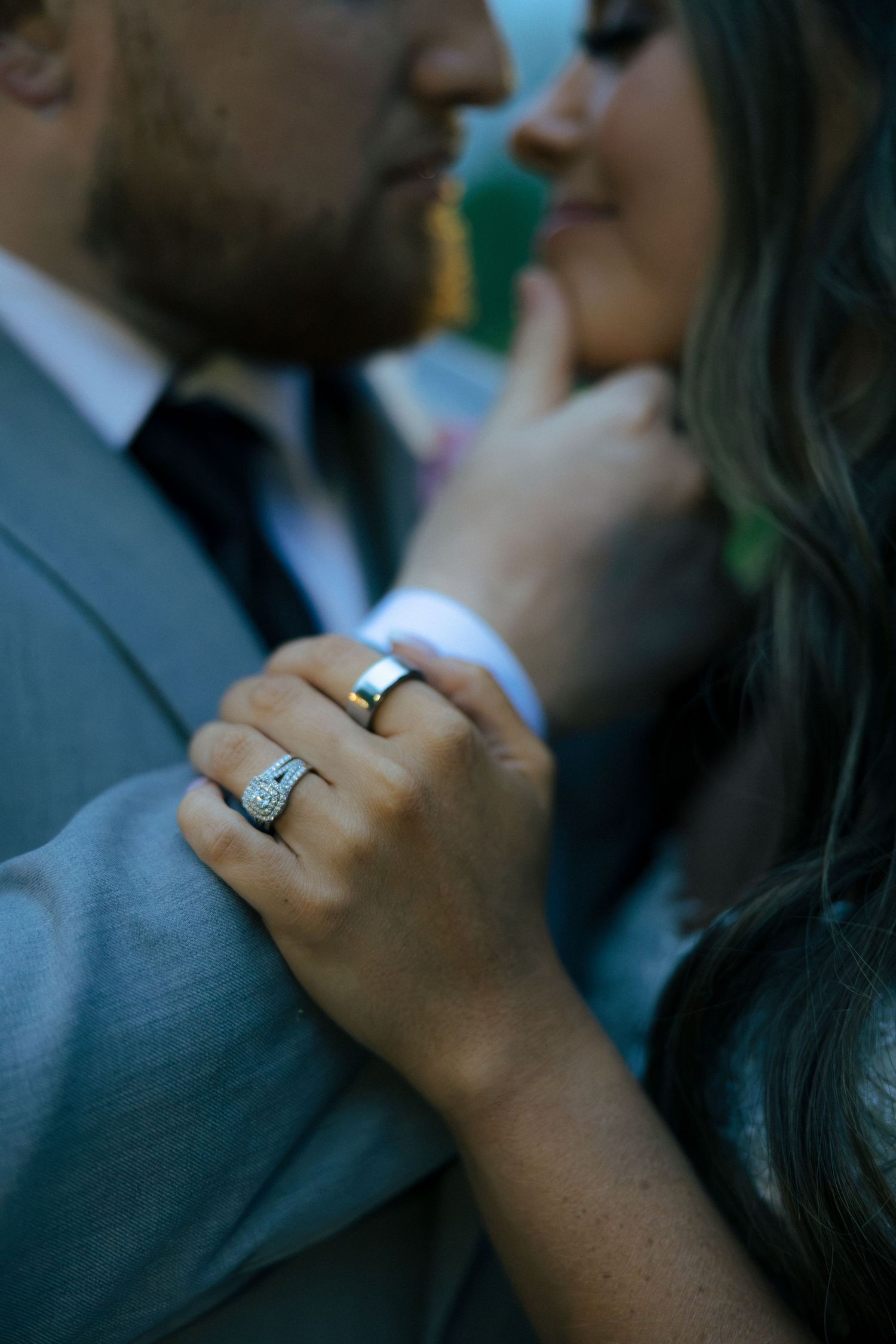 Close-up of bride and grooms hands showing wedding rings, bride wearing a diamond halo ring and groom a gold band.