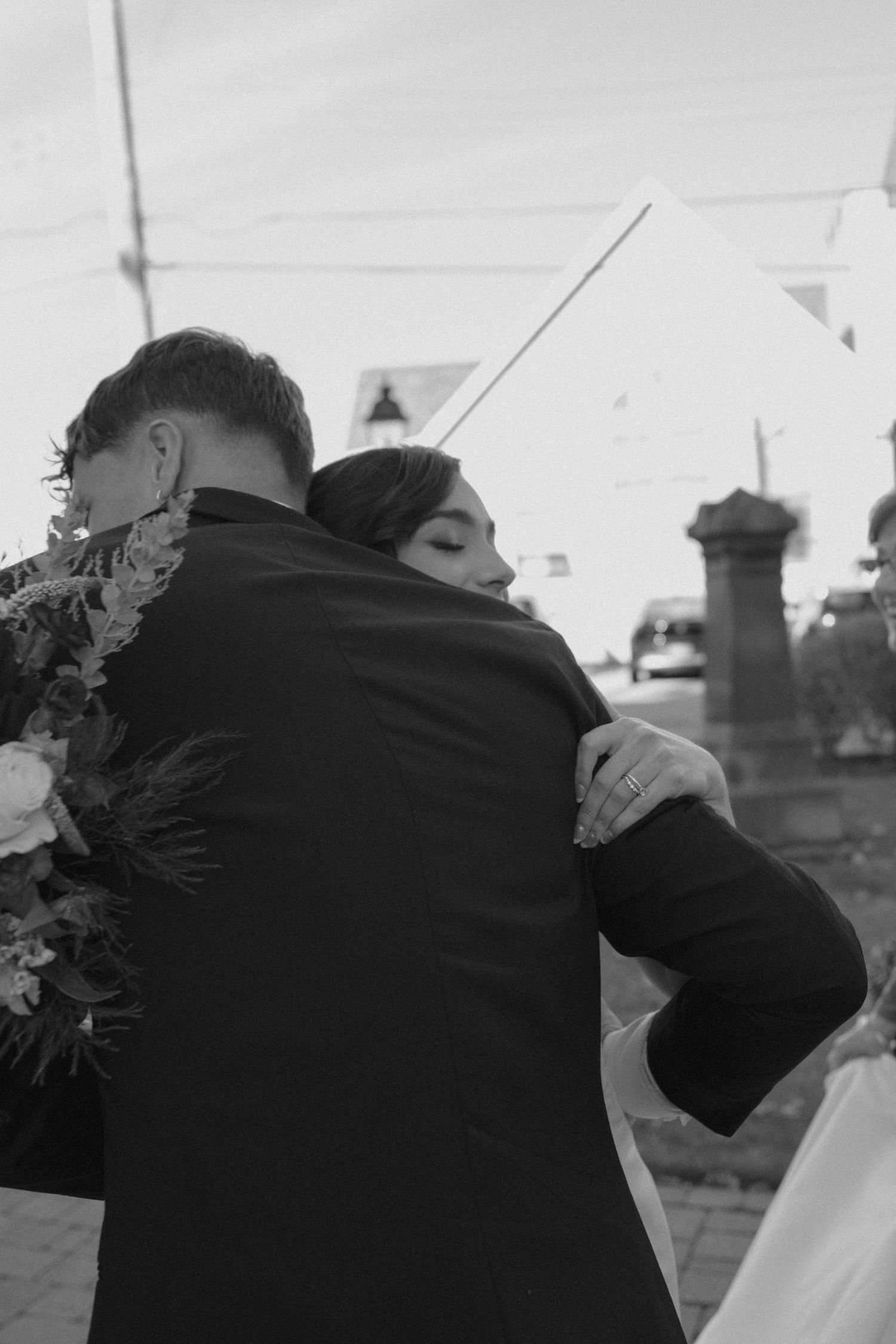 Bride and groom sharing tender embrace outdoors on their wedding day in black and white.