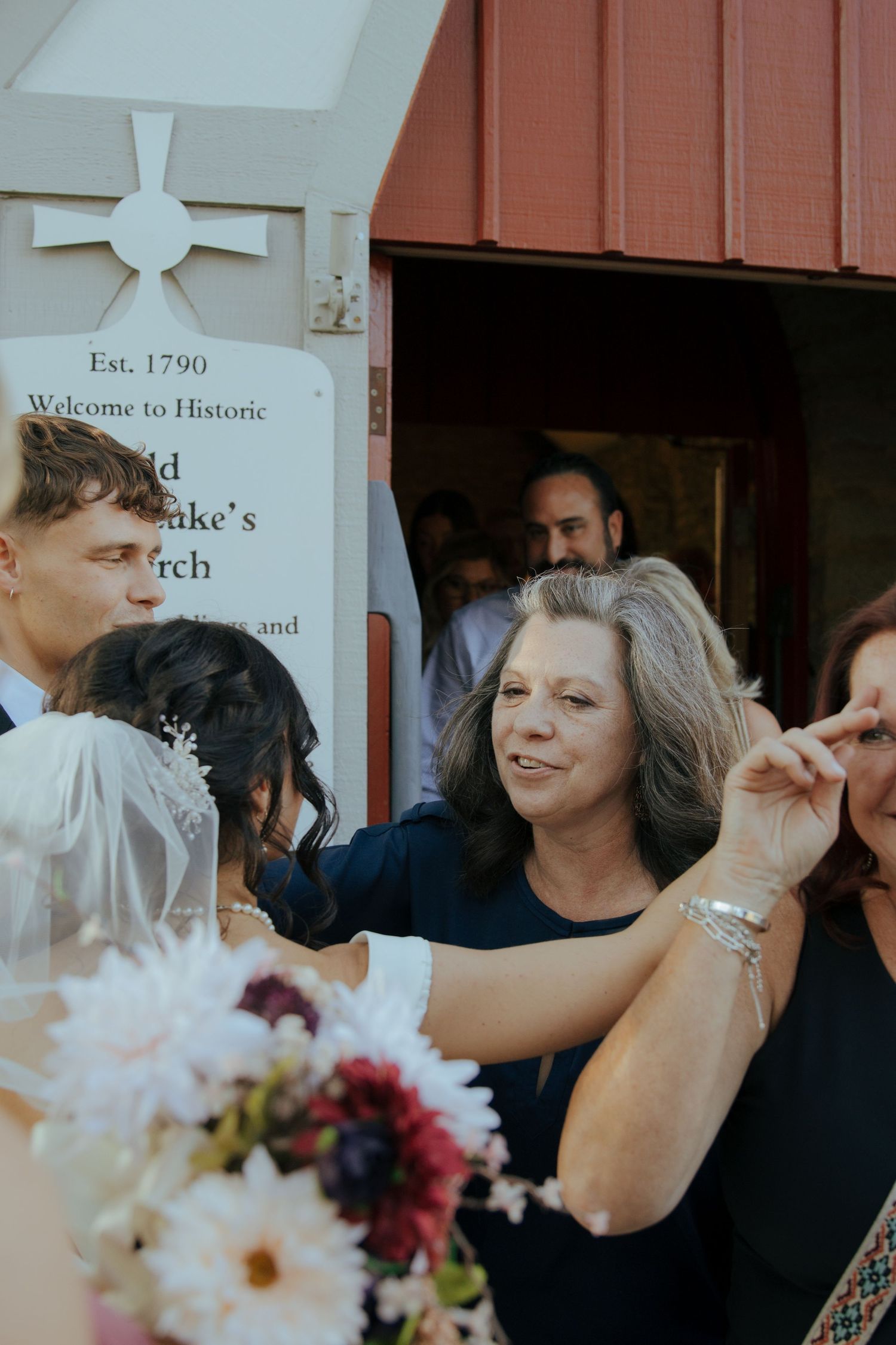 Wedding guests greet the bride and groom outside a historic church established in 1790.
