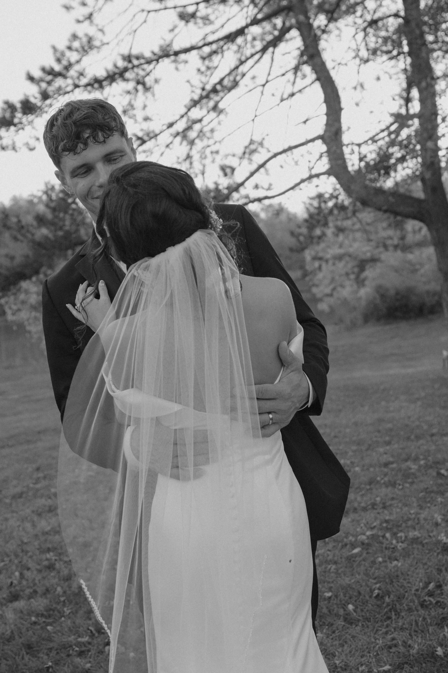 Black and white wedding portraits showing tender embraces between newlyweds in a natural outdoor setting.
