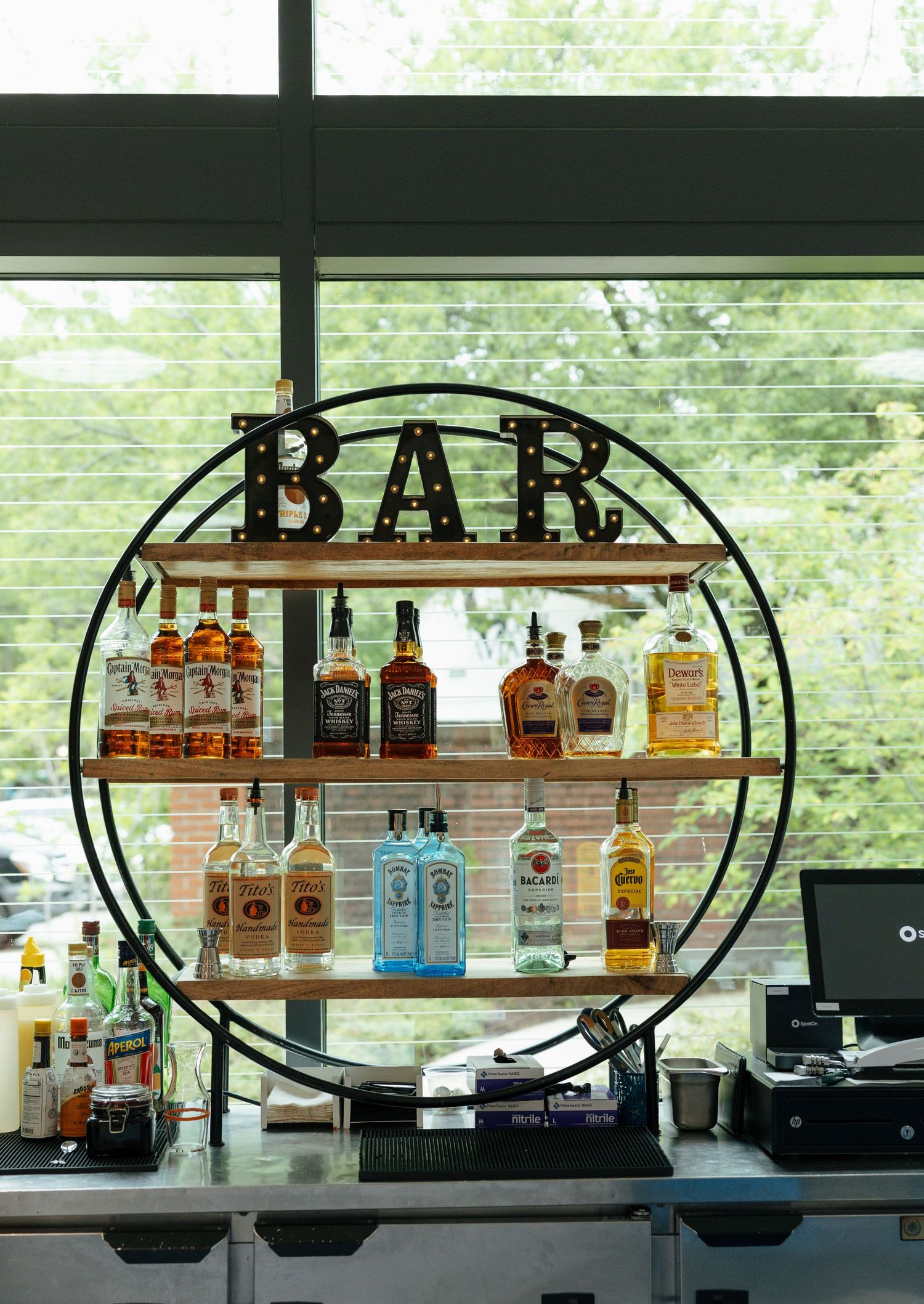 Circular bar display shelf with liquor bottles and BAR sign at a wedding venue.