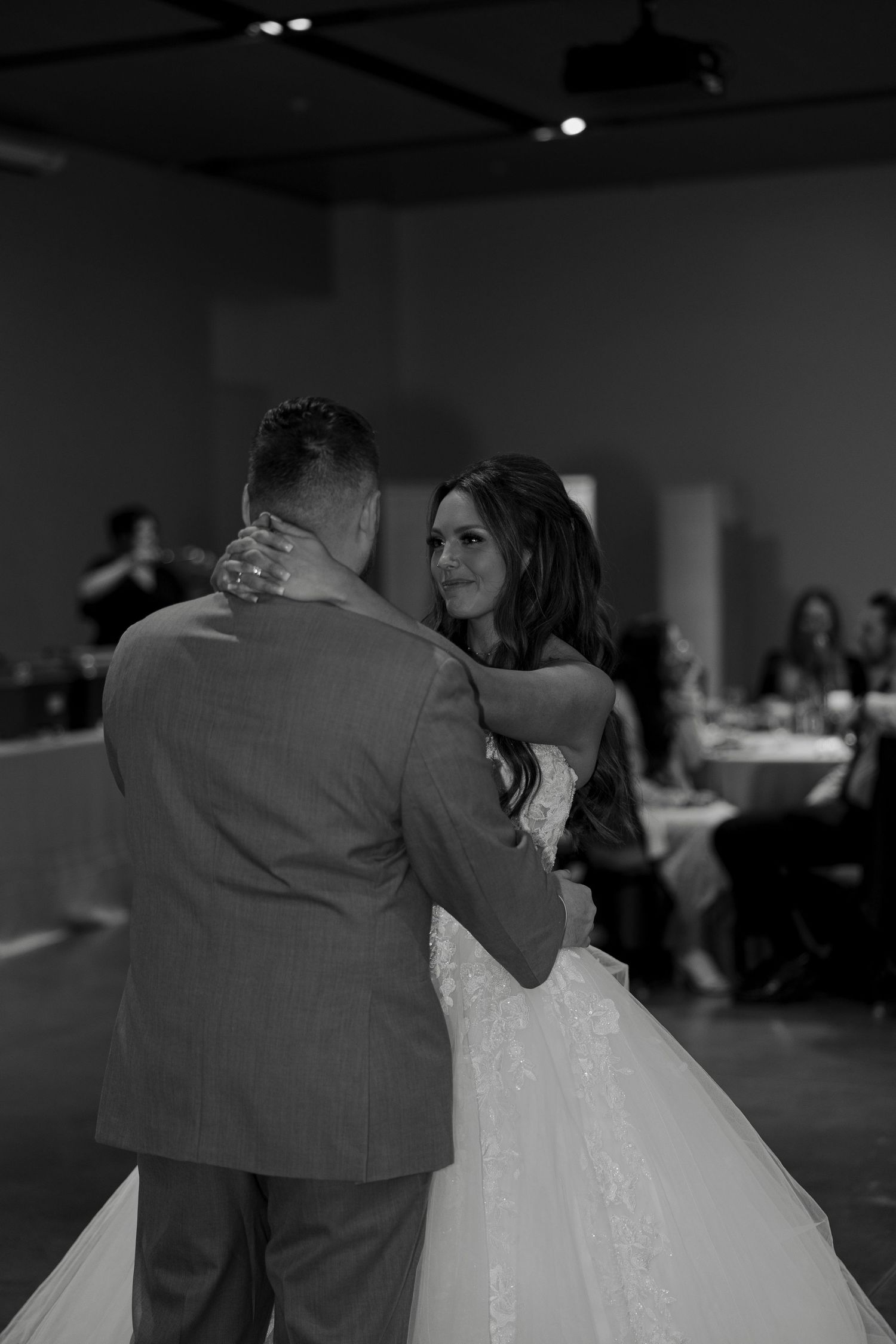 Bride and groom share their first dance in black and white wedding photo at elegant reception venue.
