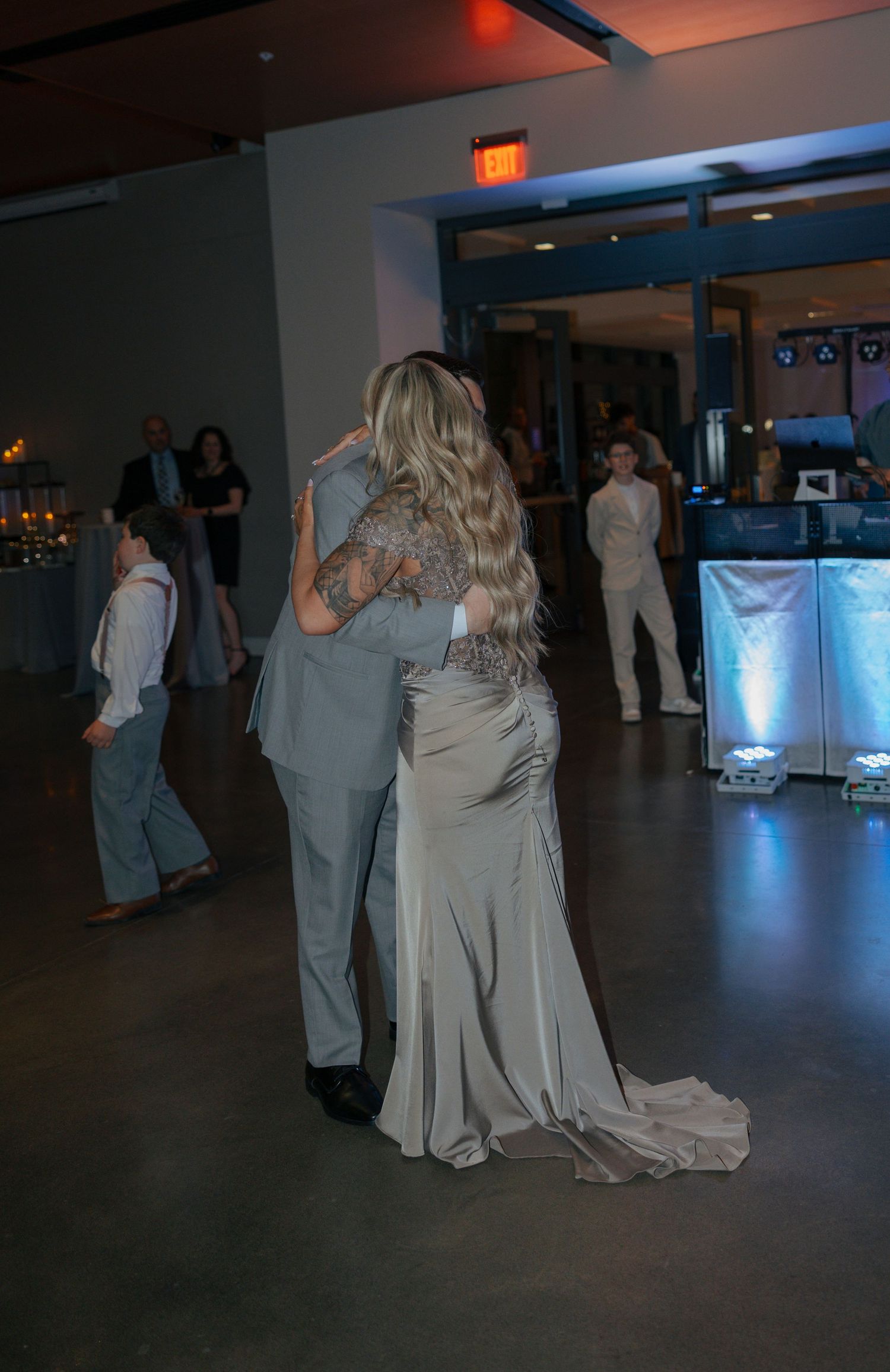 Couple sharing a first dance at a wedding reception in an elegant venue with guests watching in the background.