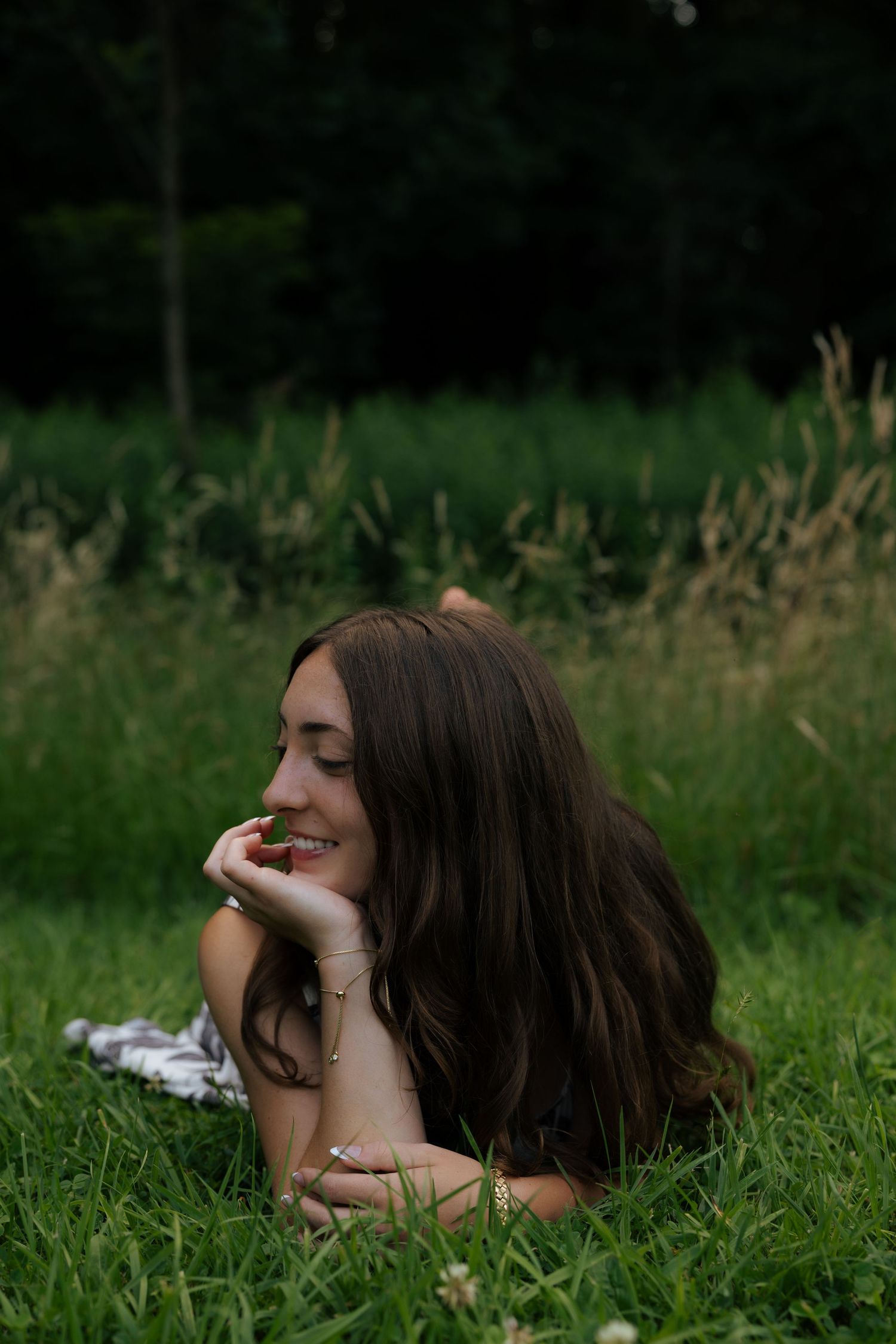 Smiling young woman lying in green grass on a sunny day.