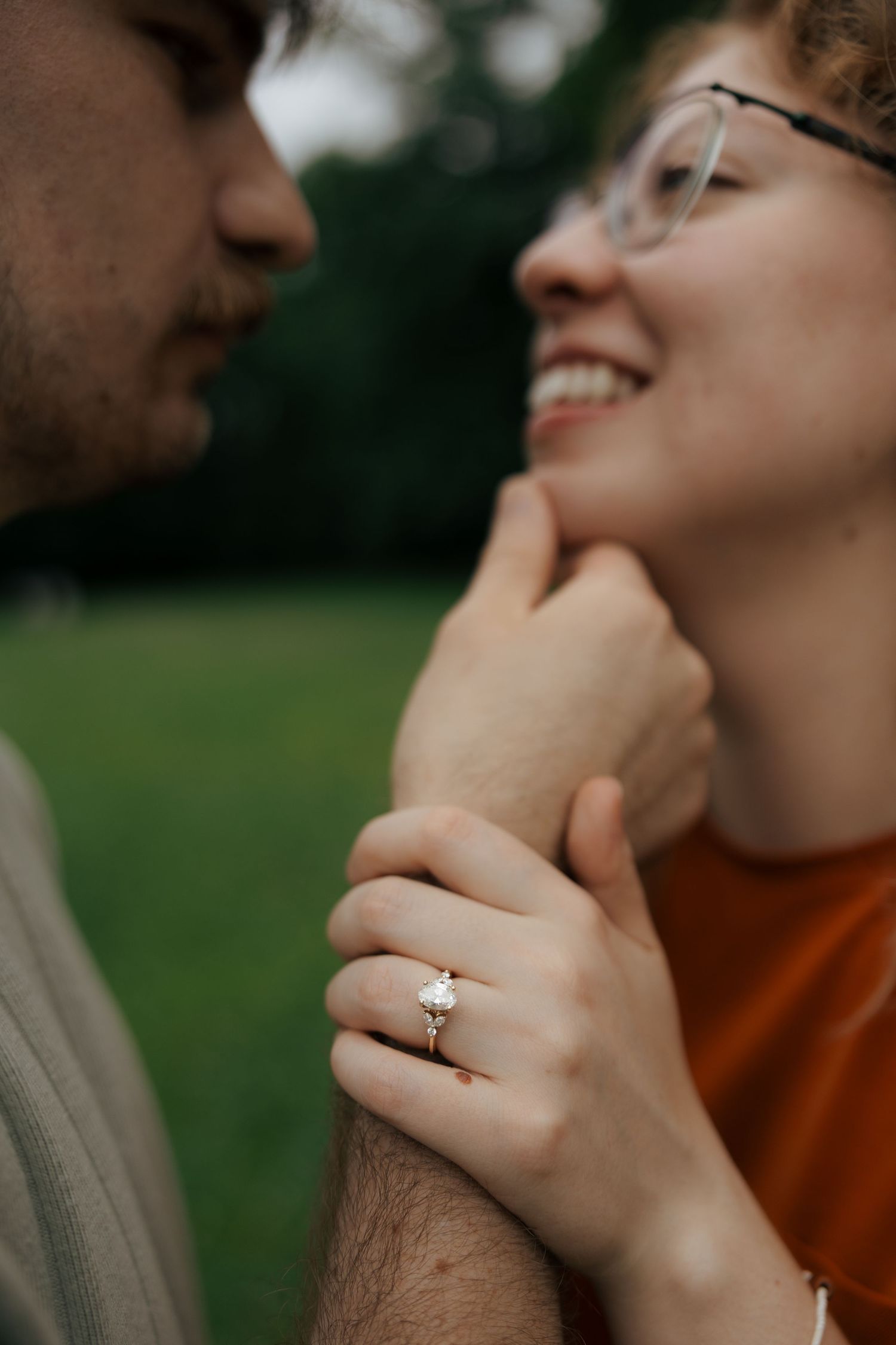Close-up of a sparkling engagement ring as couple shares a tender romantic moment outdoors.