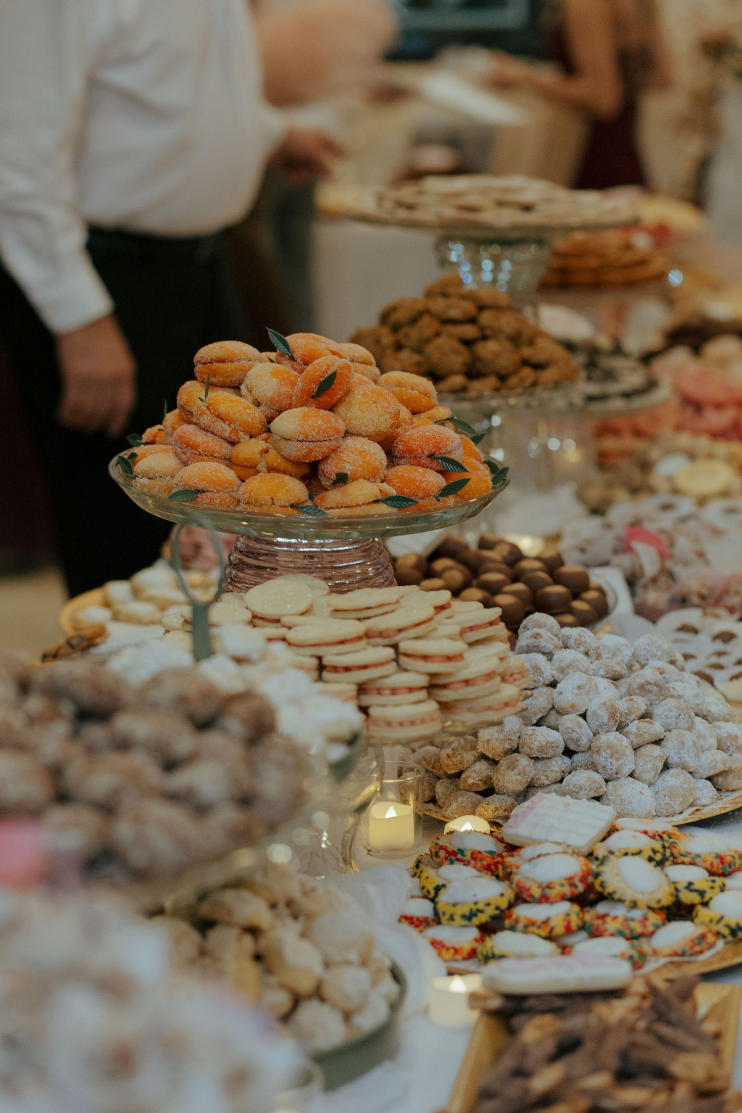 Elegant wedding dessert table featuring an assortment of cookies, pastries, and sweets displayed on tiered glass stands.