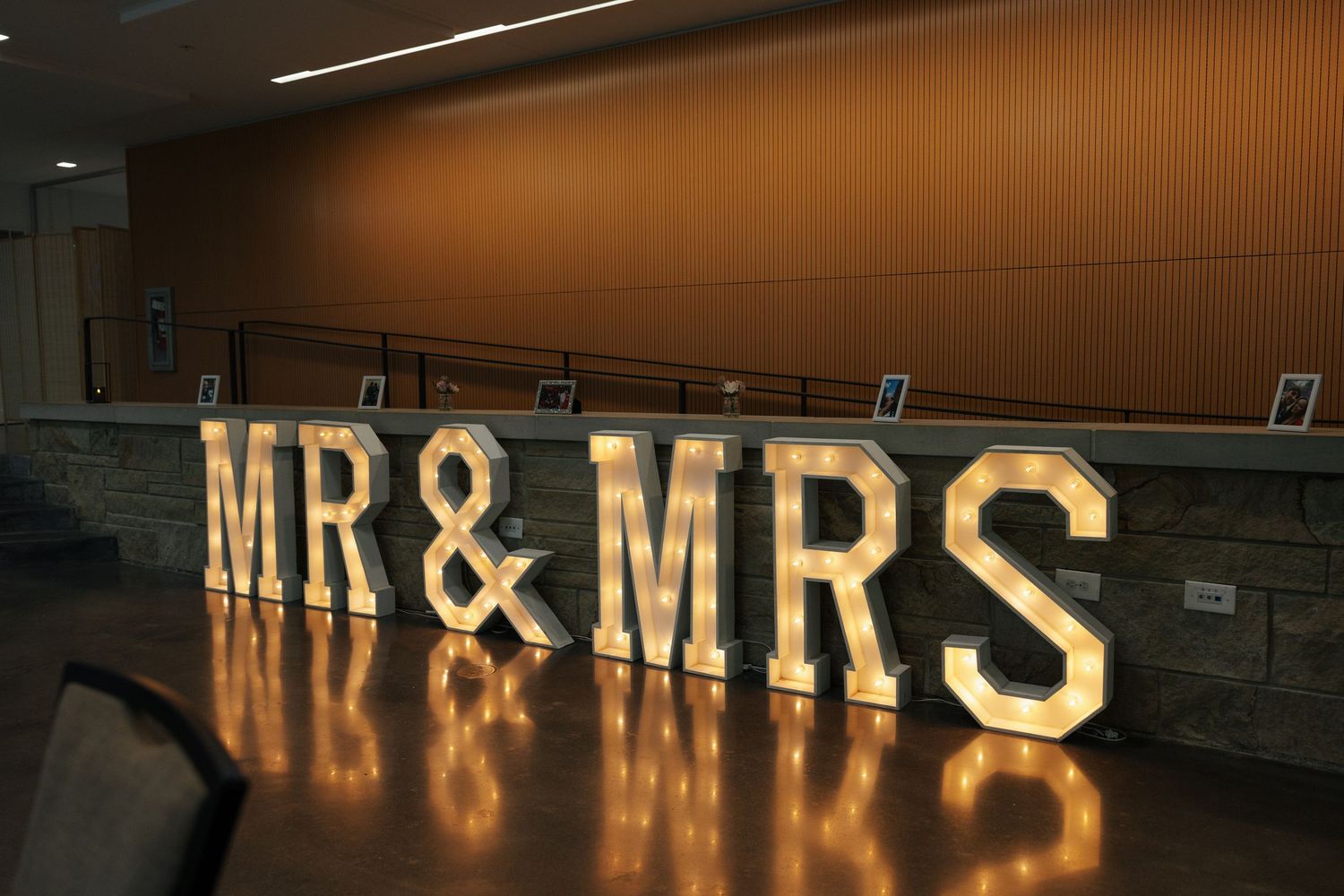 Illuminated marquee letters spelling MR & MRS displayed at a wedding reception venue.