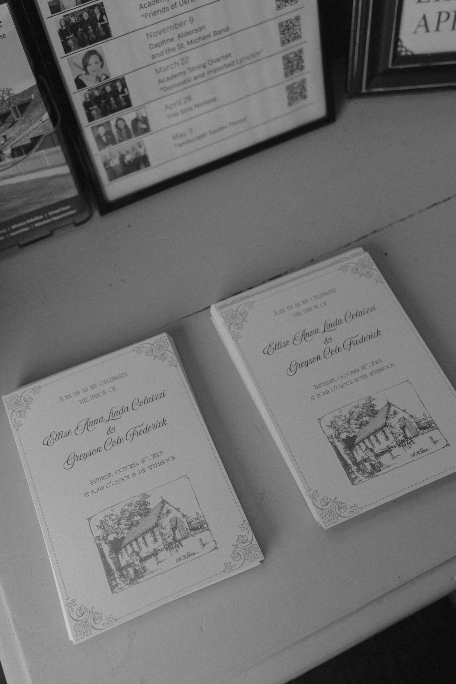 Black and white photo of two elegant wedding programs on a table, featuring illustrated church artwork and decorative borders.