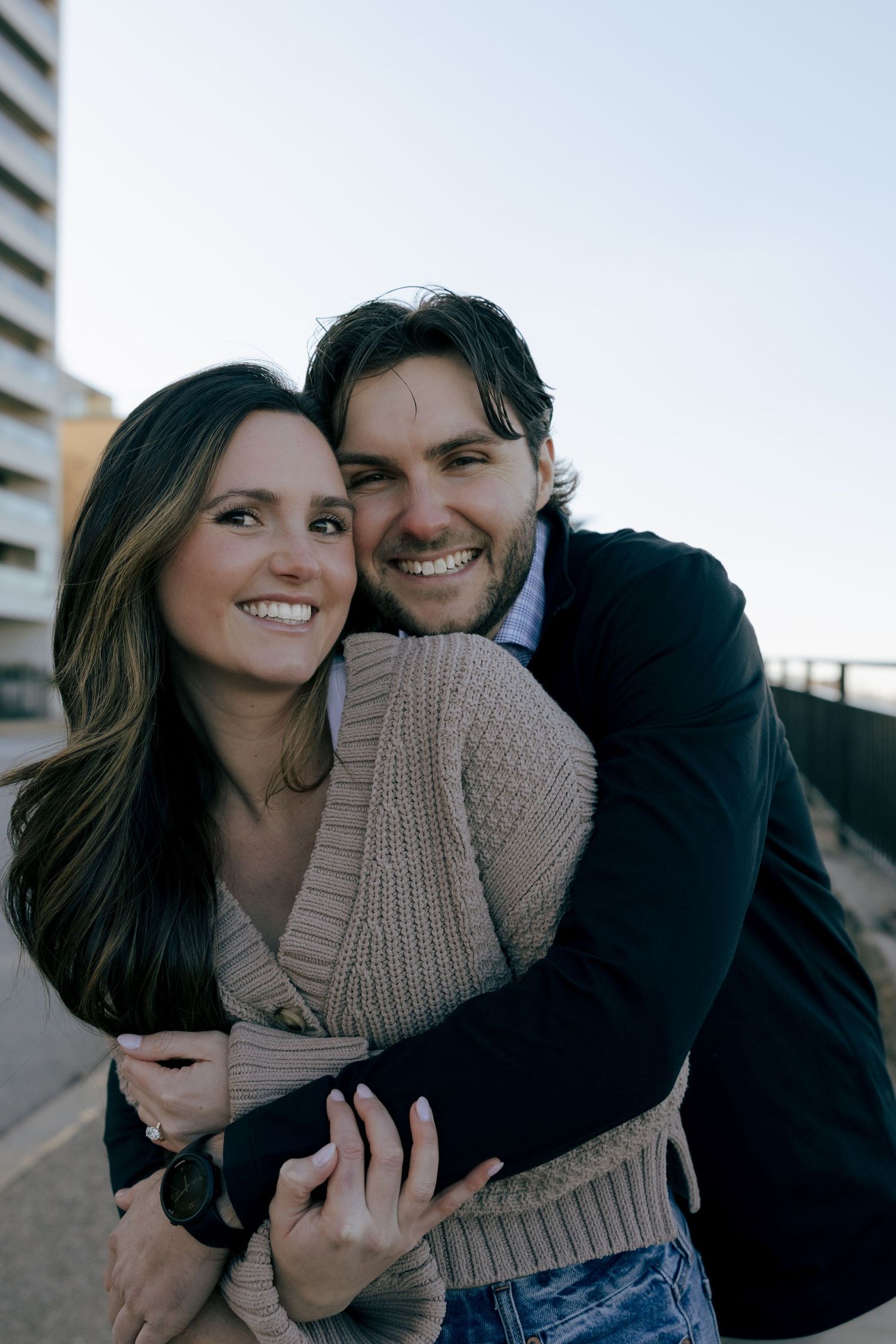 A couple embraces and laughs together while sharing a playful moment outdoors.