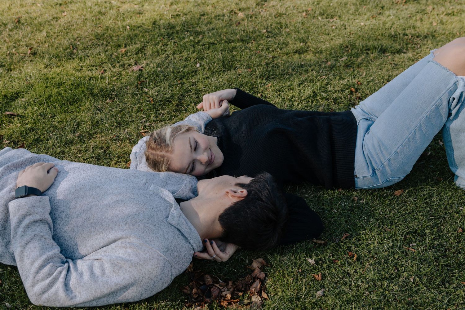 Person relaxing and lying down on green grass lawn on a sunny day.