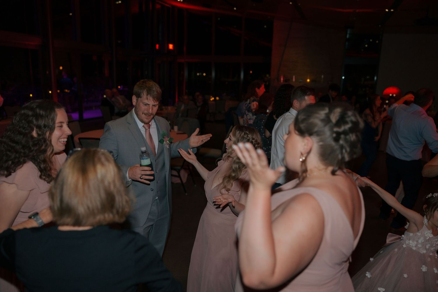 Wedding guests dancing and celebrating together on the dance floor during a lively evening reception.