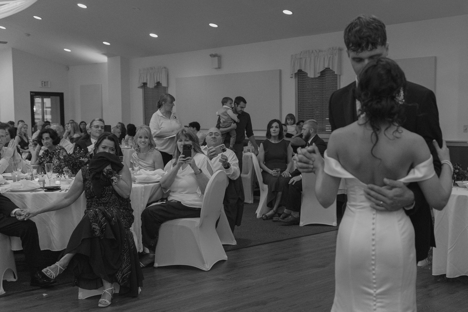 Bride and groom share their first dance as wedding guests watch in an elegant reception hall.
