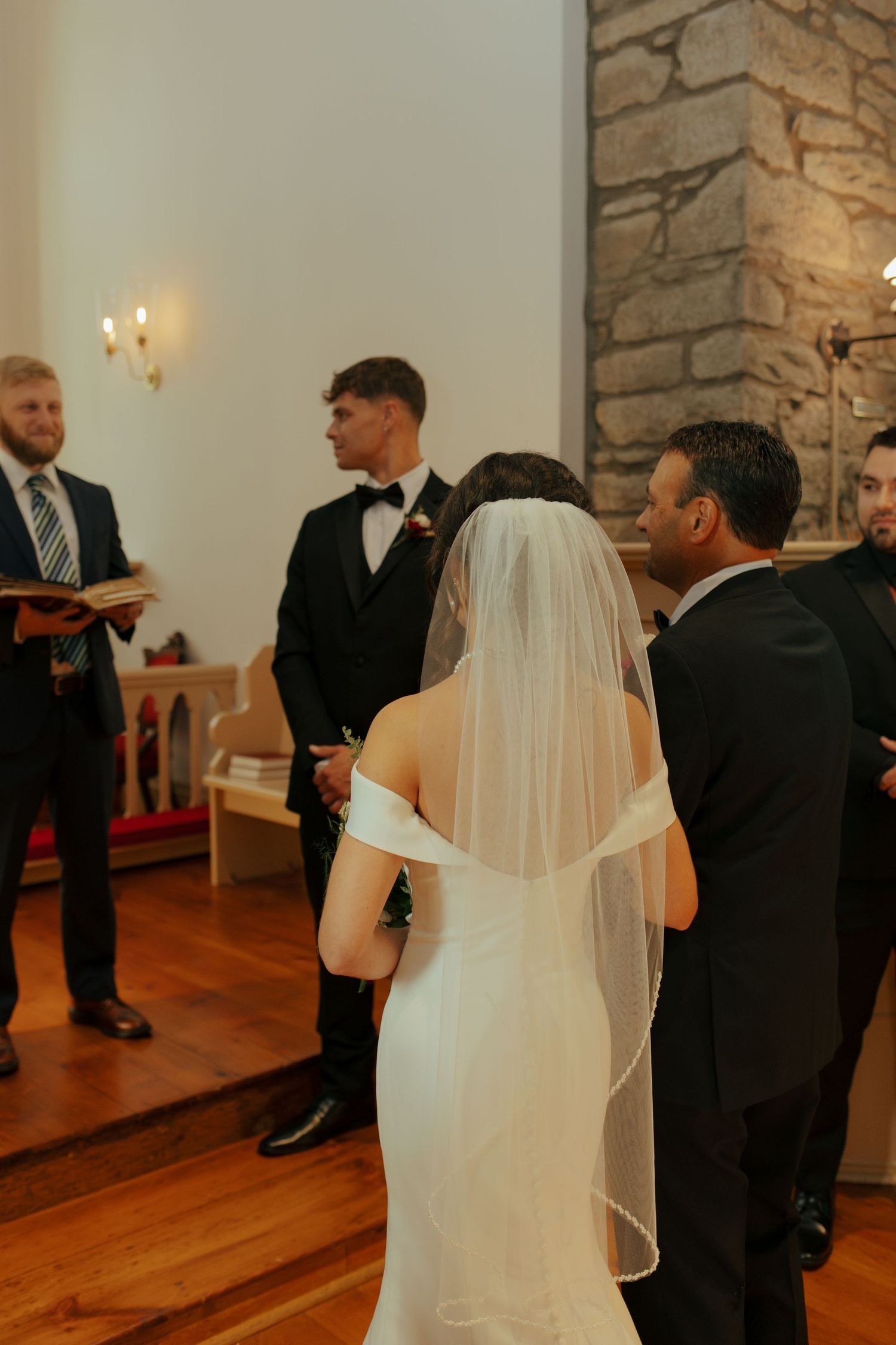 Bride in white gown and veil standing at altar with groom during church wedding ceremony.