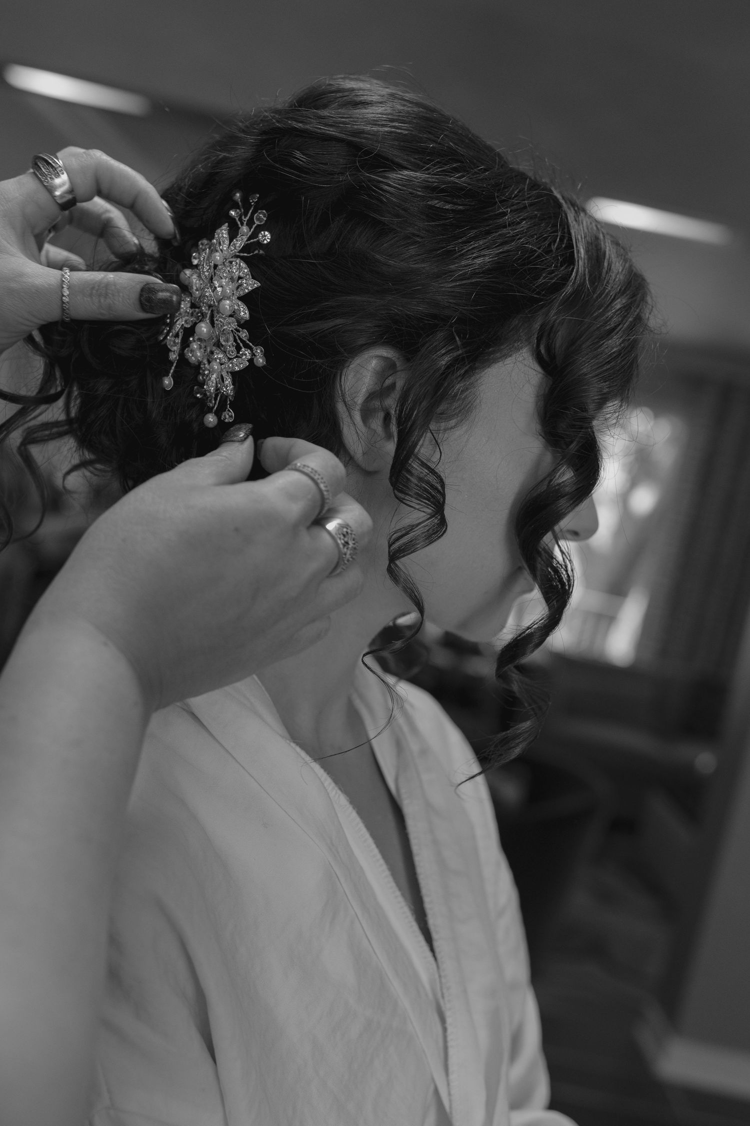 Black and white photo of bride having floral hair accessory placed in elegant updo hairstyle.