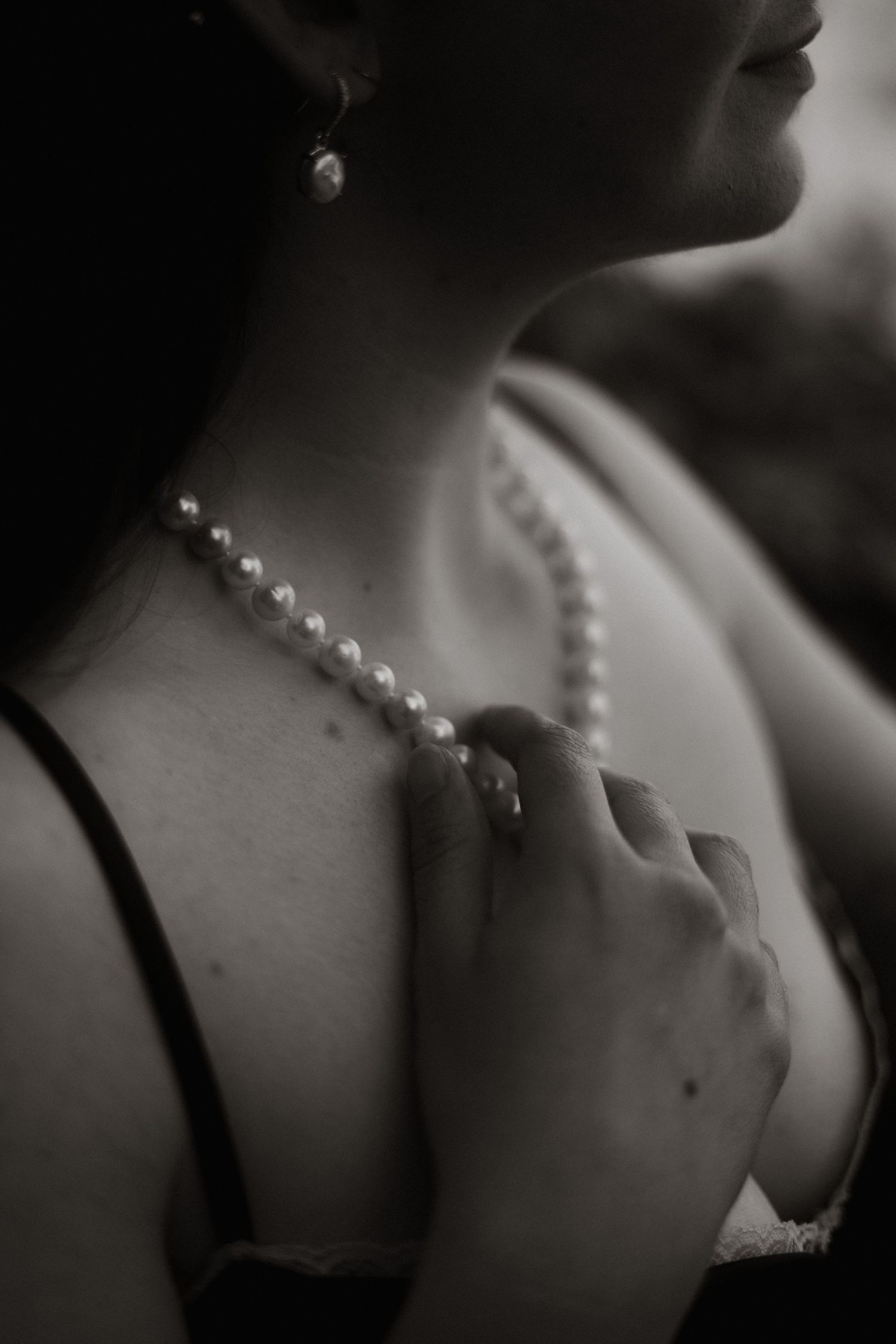 Girl touches pearls on her neck, black and white photo, dreamy and ethereal in Edinburgh, Scotland.
