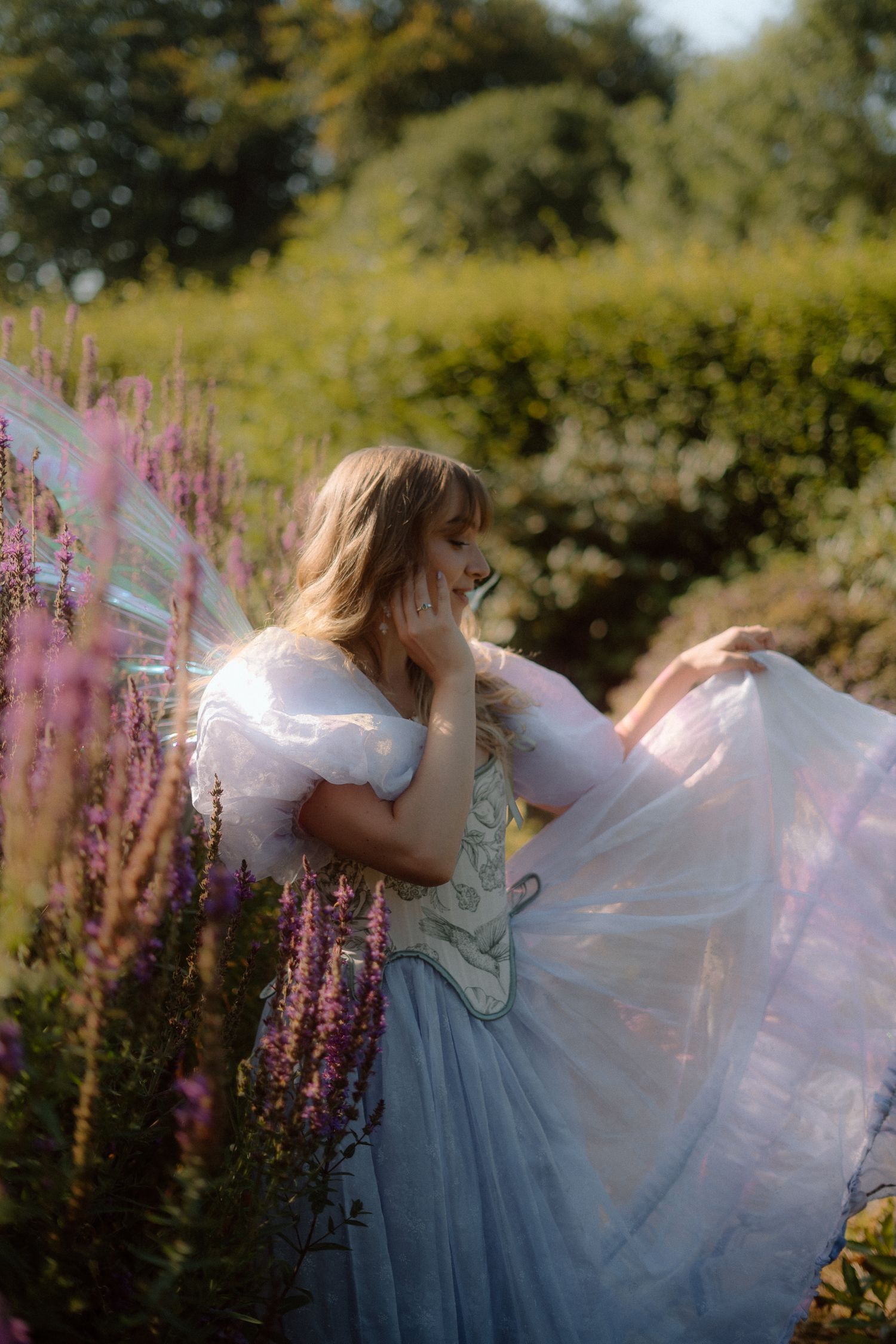 A dreamy scene in a garden with flowing blue and white dress twirling among pink wildflowers in golden sunlight.