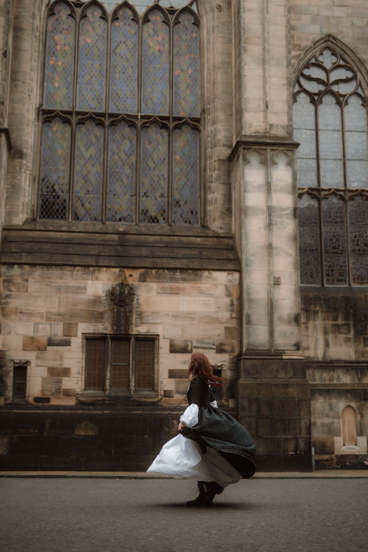 A wedding photographer captures a bride and groom in a series of romantic poses against a historic stone cathedral wall.