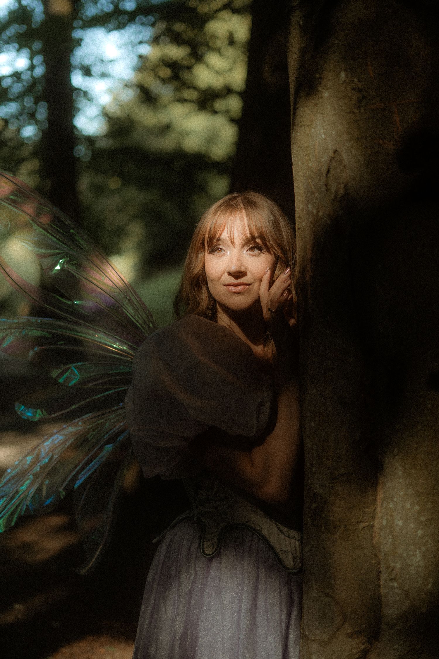 A dreamy portrait in a forest setting with soft lighting and dark feathers creating an ethereal atmosphere.