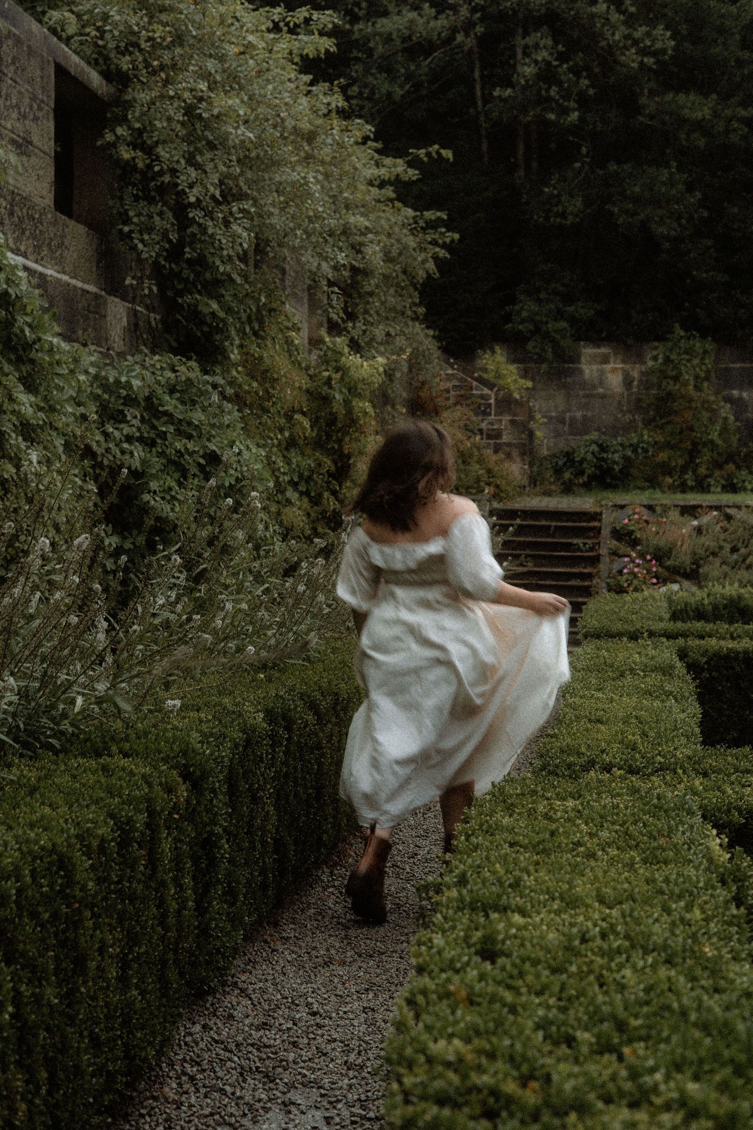 Women dressed in white dress runs through an Italian garden. cottagecore vibes. Pollok Park, Scotland.