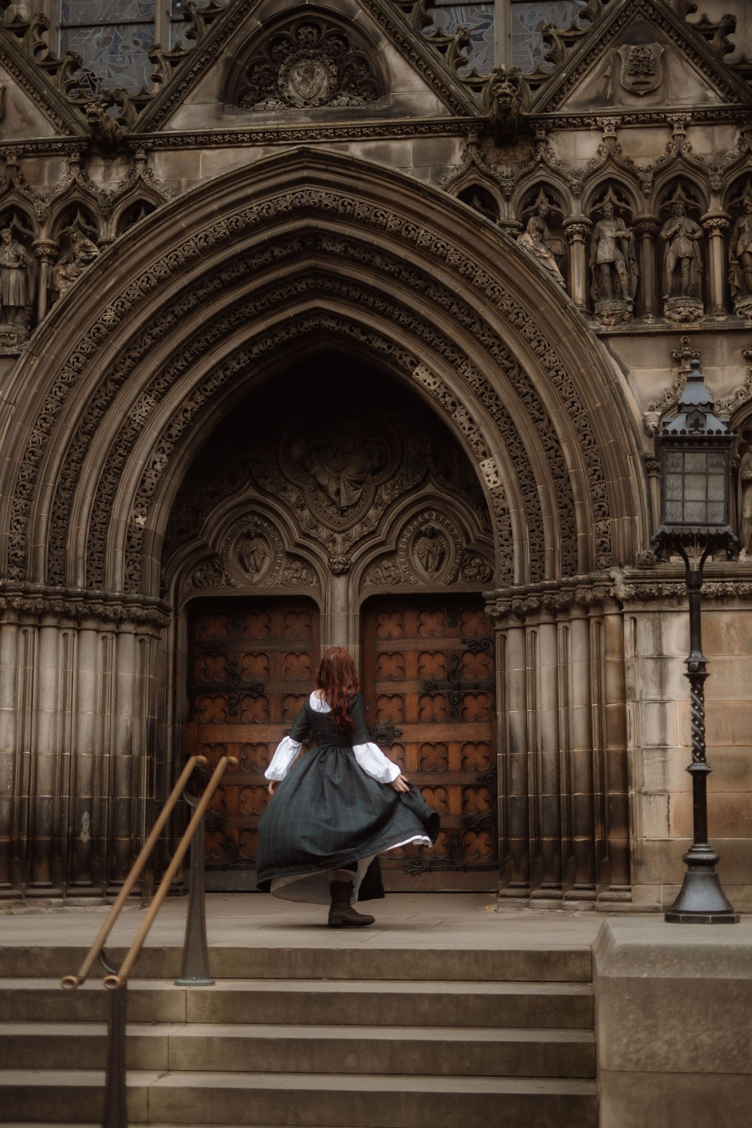 A person in a flowing dress spins in front of ornate Gothic cathedral doors with intricate stone archways.