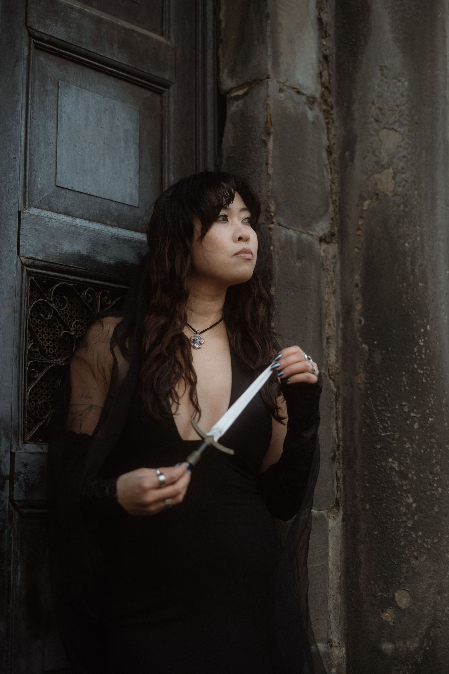 A person in a dark dress poses dramatically against a weathered wall in a moody gothic photoshoot sequence.