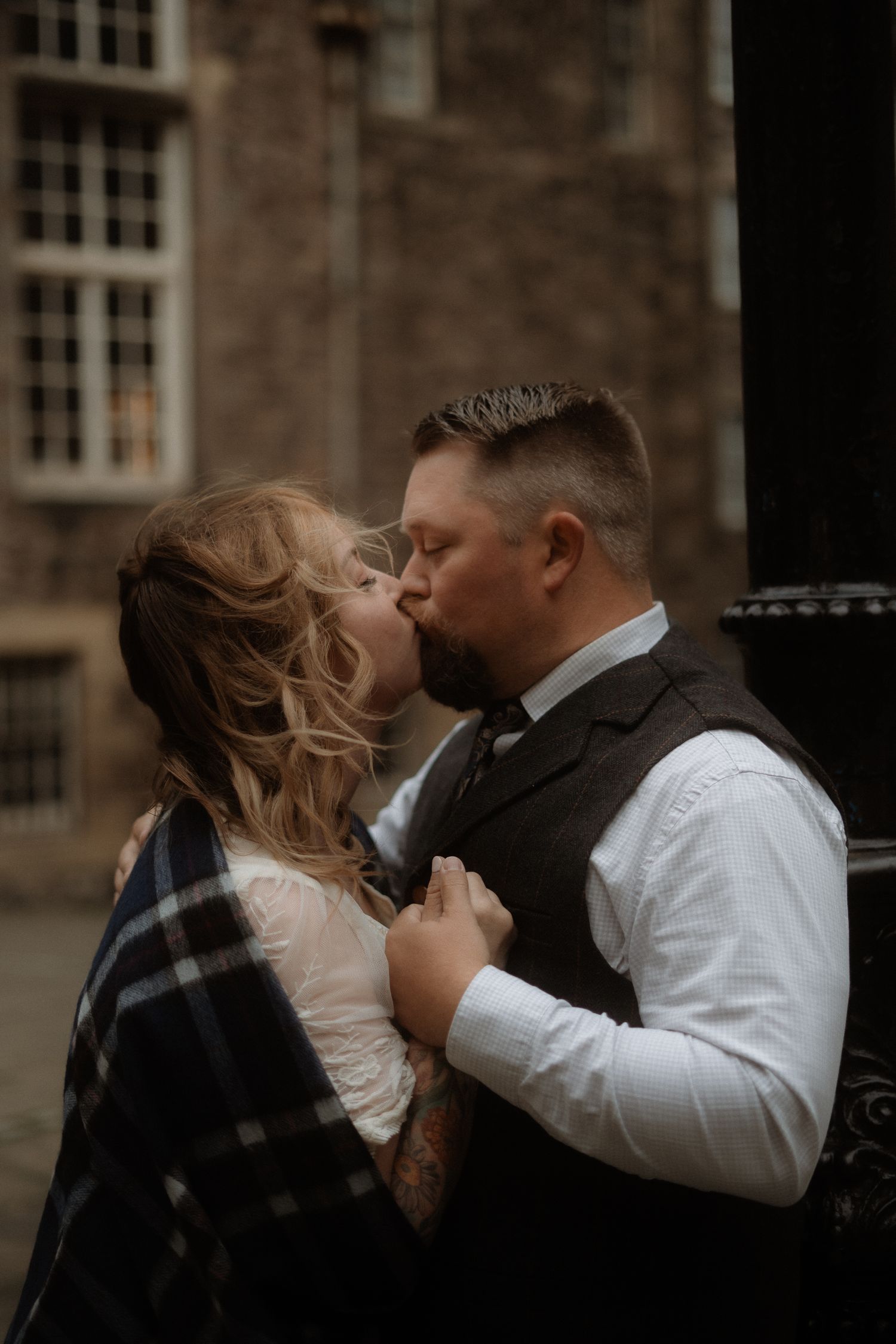 A romantic moment captured against a historic stone building backdrop.