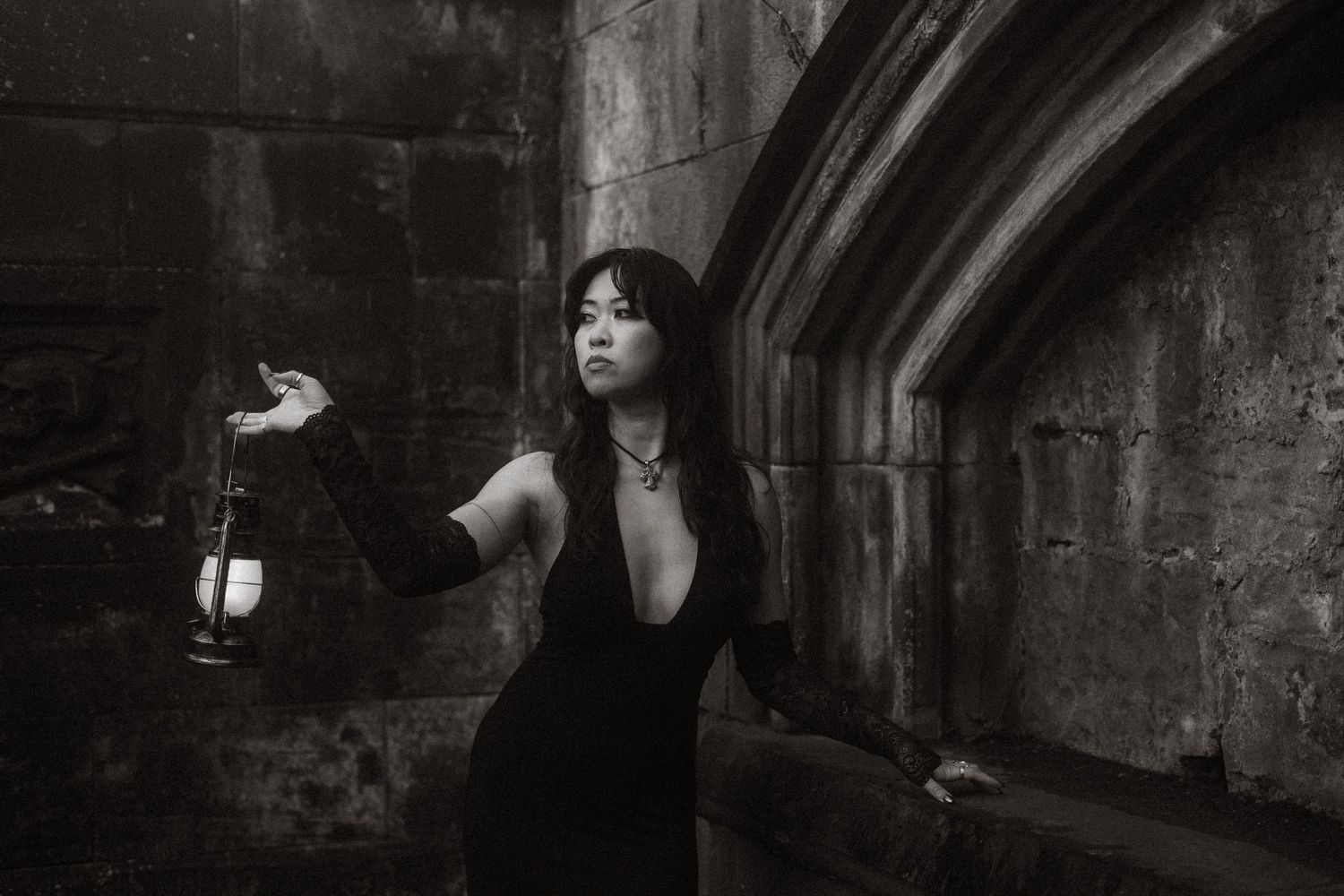 A person performs dramatic dance movements in a dark urban tunnel with moody lighting and shadows.