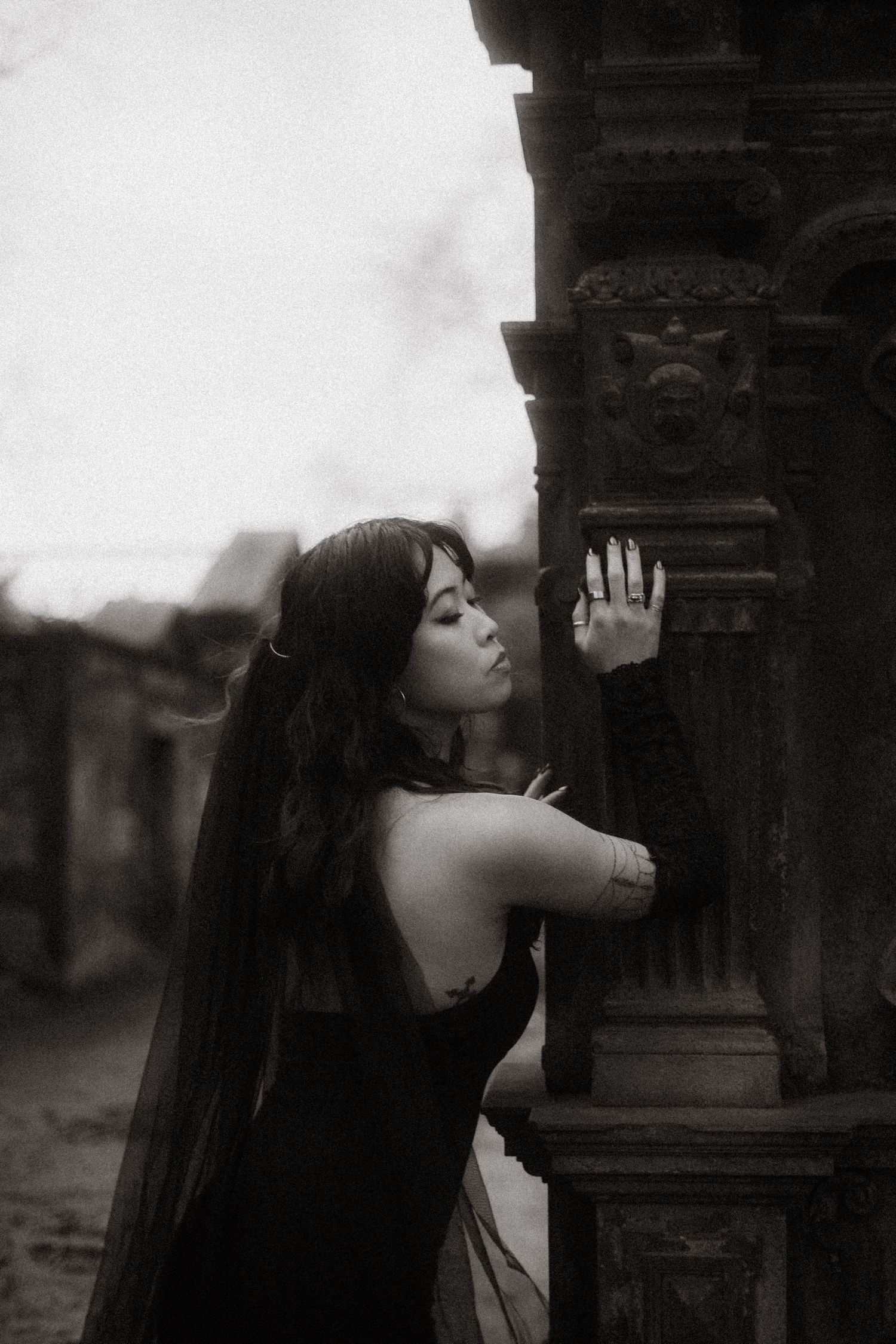 A dramatic black and white photo series showing a figure in dark clothing leaning against stone architecture.