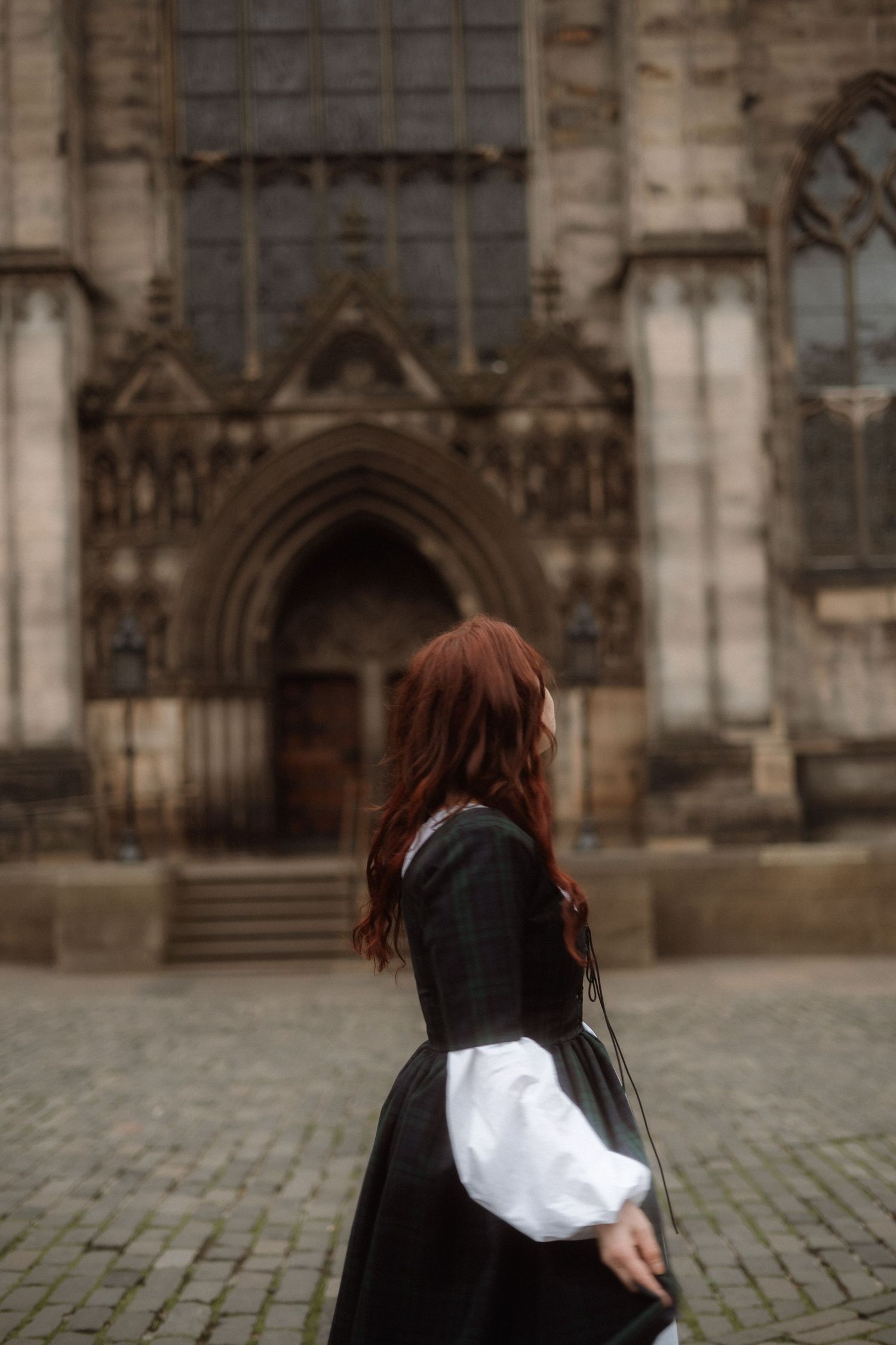 A sequence of images showing a person in black clothing spinning around on cobblestones in front of a Gothic cathedral.