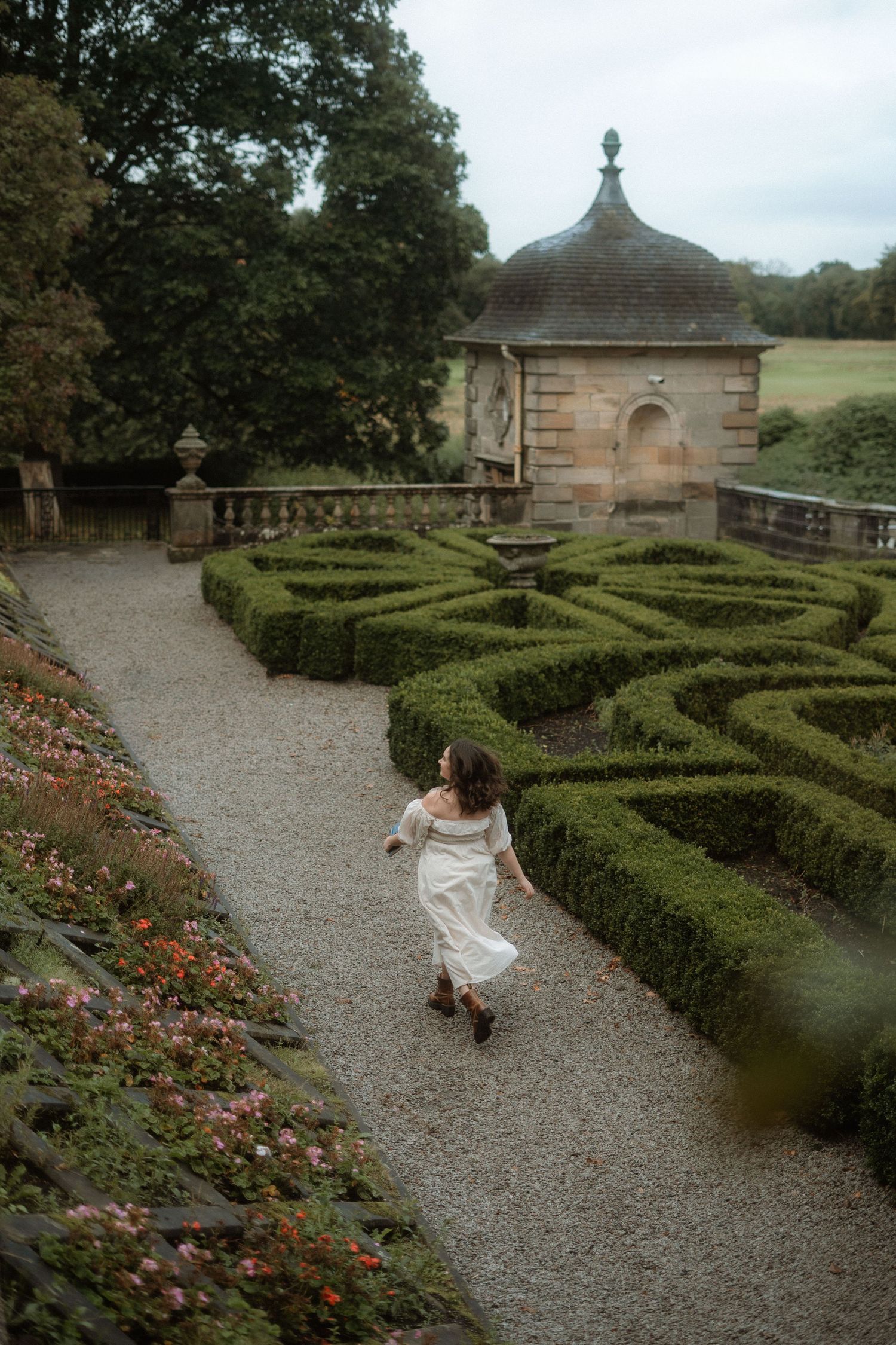 Women dressed in white dress runs through an Italian garden. cottagecore vibes. Pollok Park, Scotland.