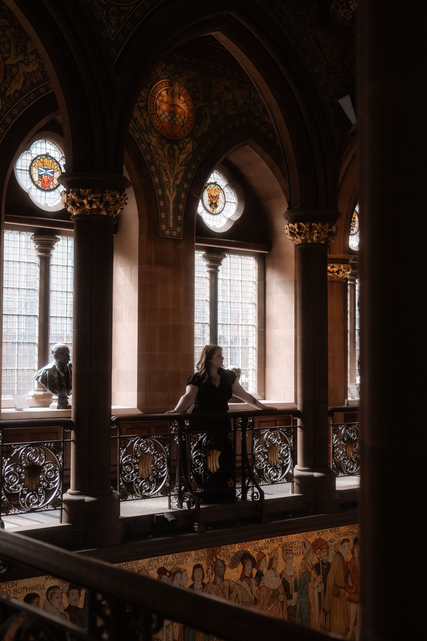 Elegant woman poses under arches in art gallery, National Portrait Gallery in Edinburgh, Scotland.
