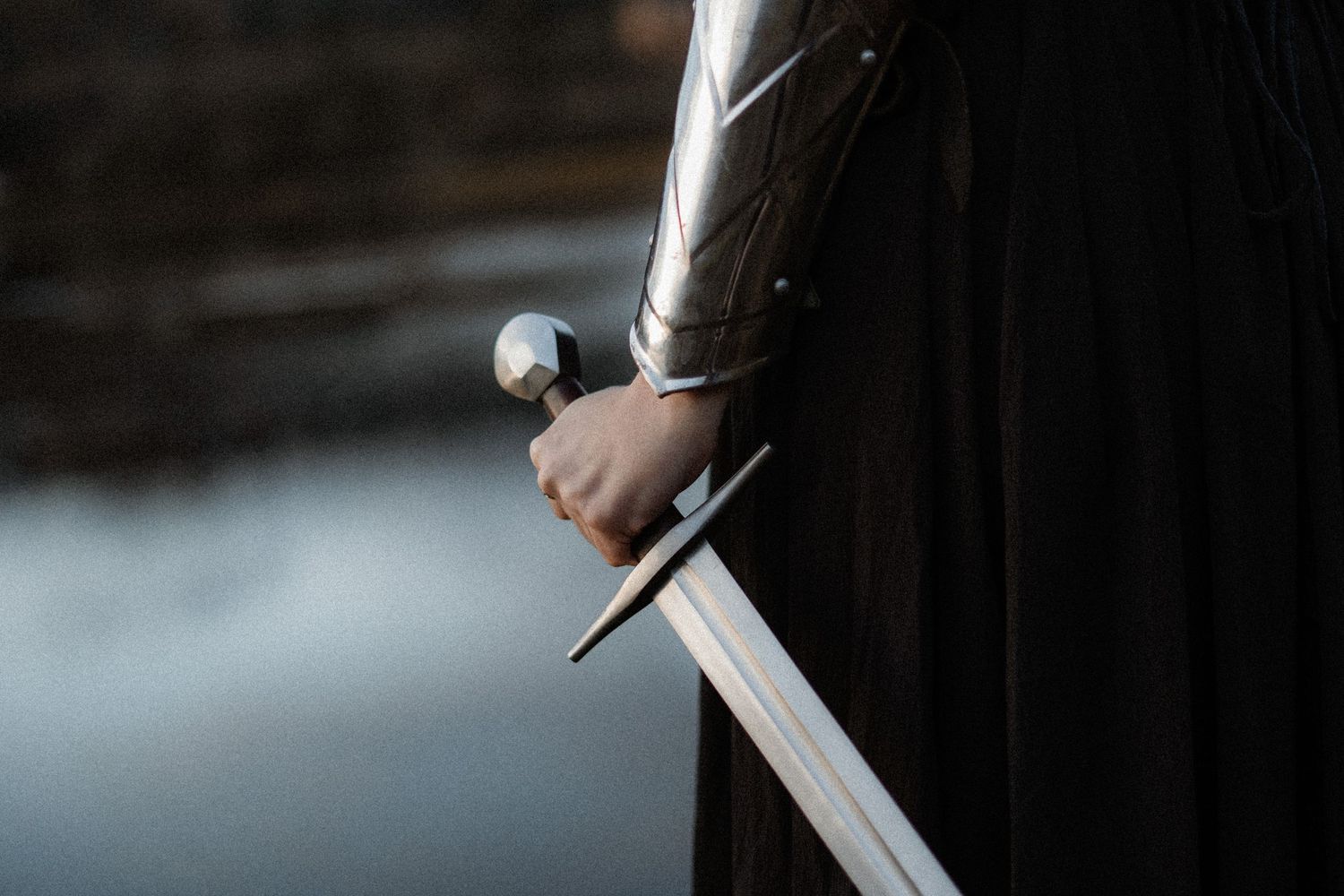 A hand holding a katana sword with a dark background, showing intricate details of the blade and handle.