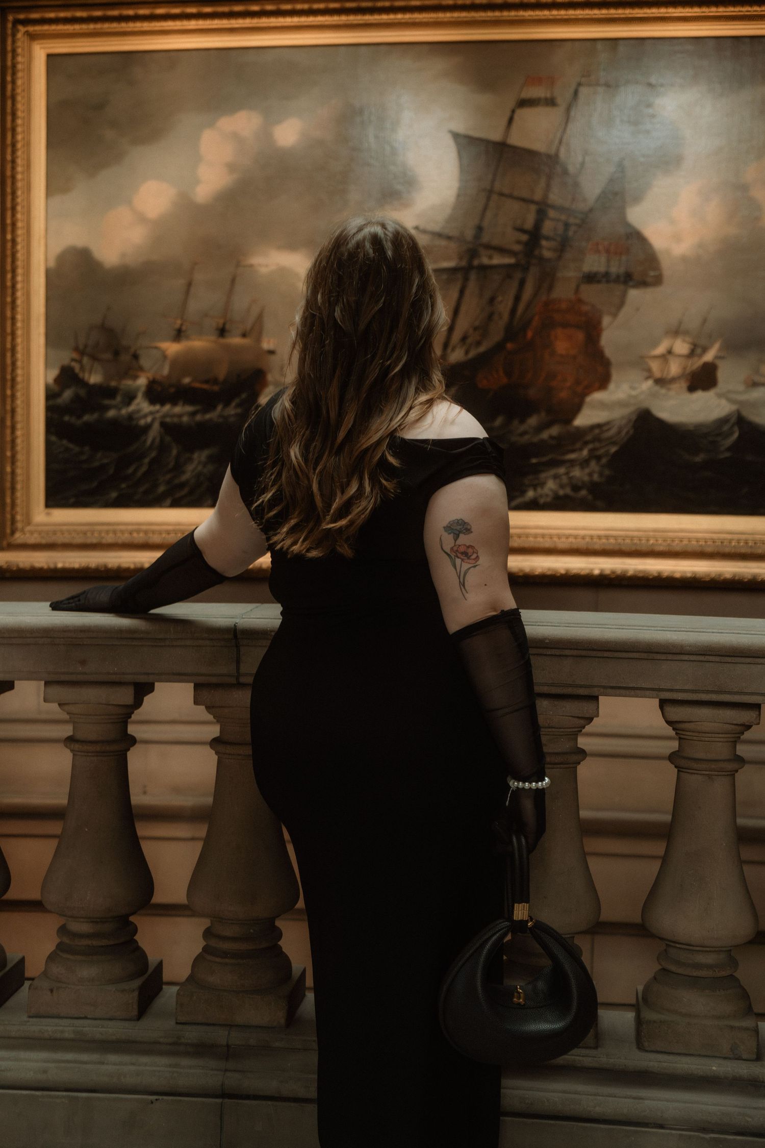 Elegant woman dressed in black with black gloves and pearls, stands next to an painting in an art gallery, Kelvingrove Art Gallery, Glasgow
