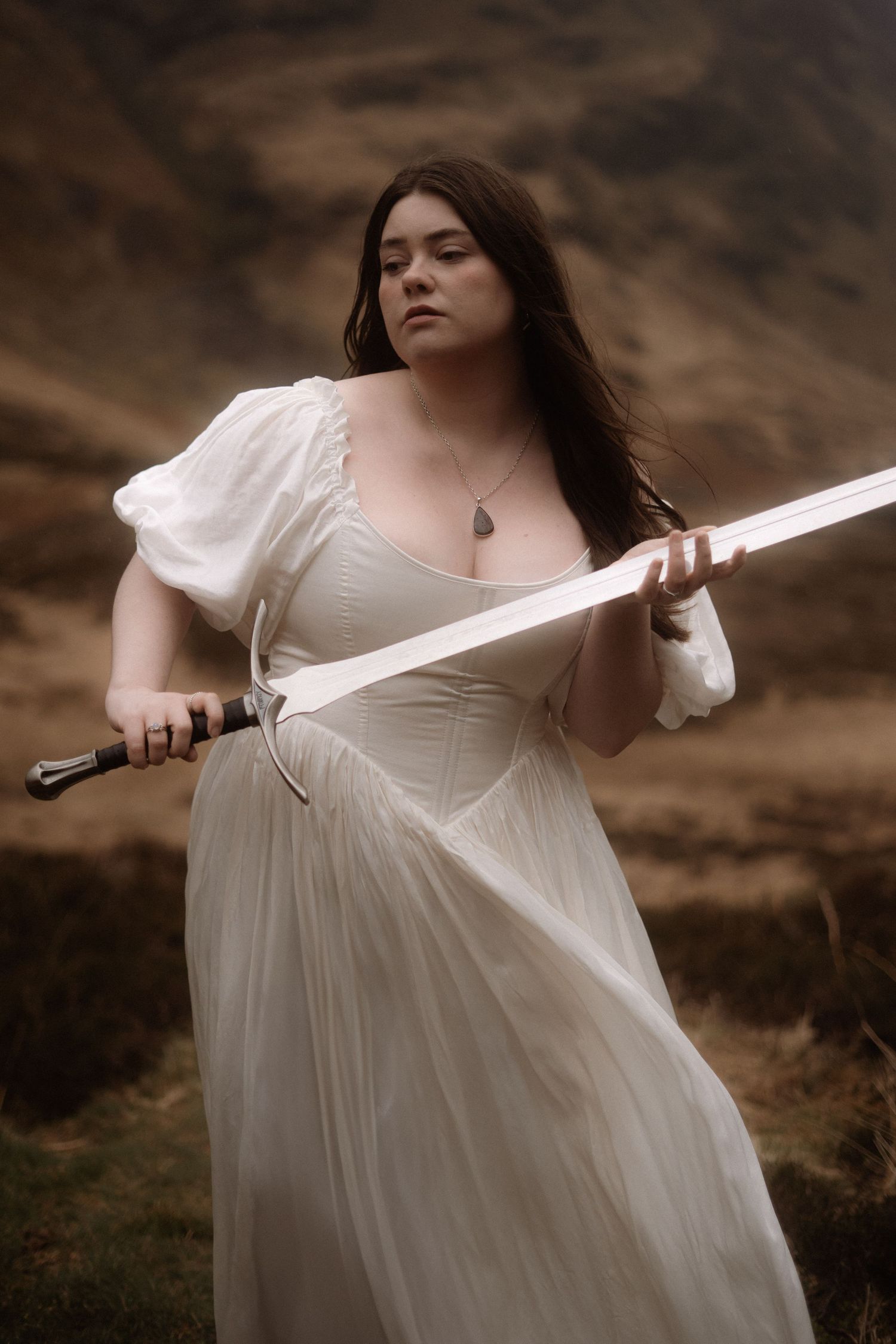 Figure in white dress wielding sword against dramatic landscape.