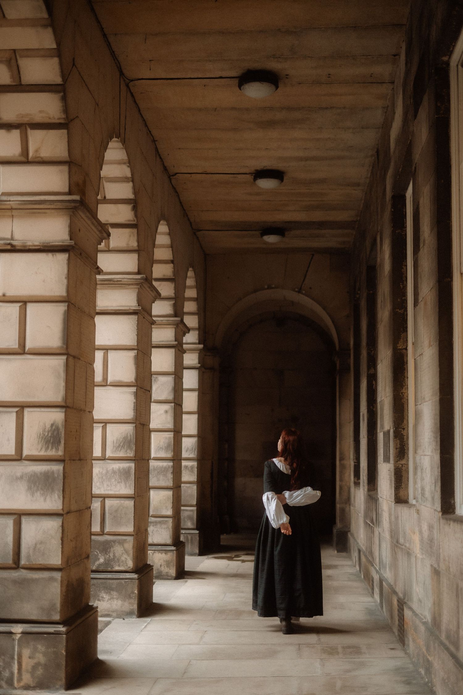 A series of four connected images showing a historic stone colonnade hallway with arched columns and figures in dark robes.