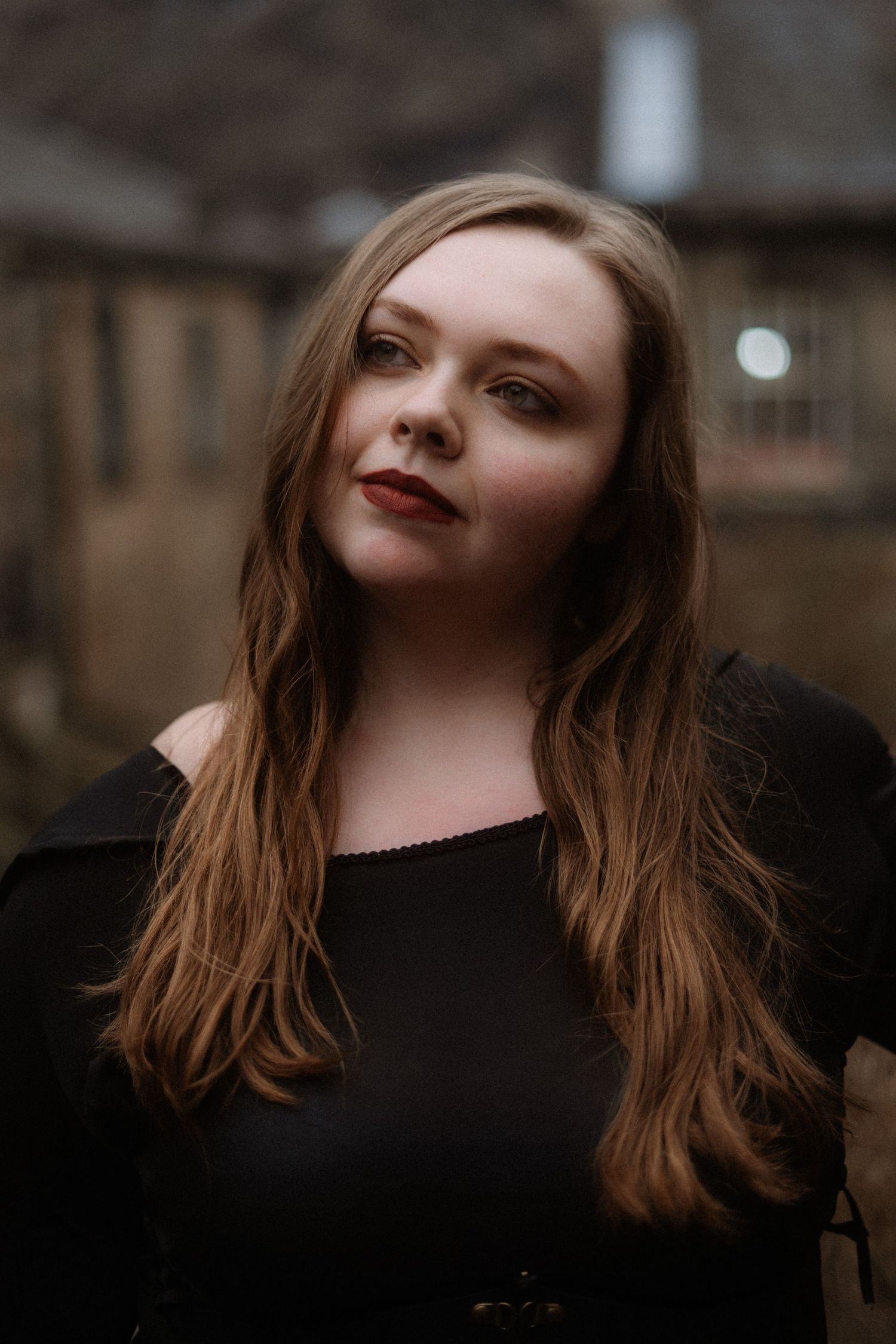 A series of moody portrait shots showing someone with brown hair wearing black against a blurred background.