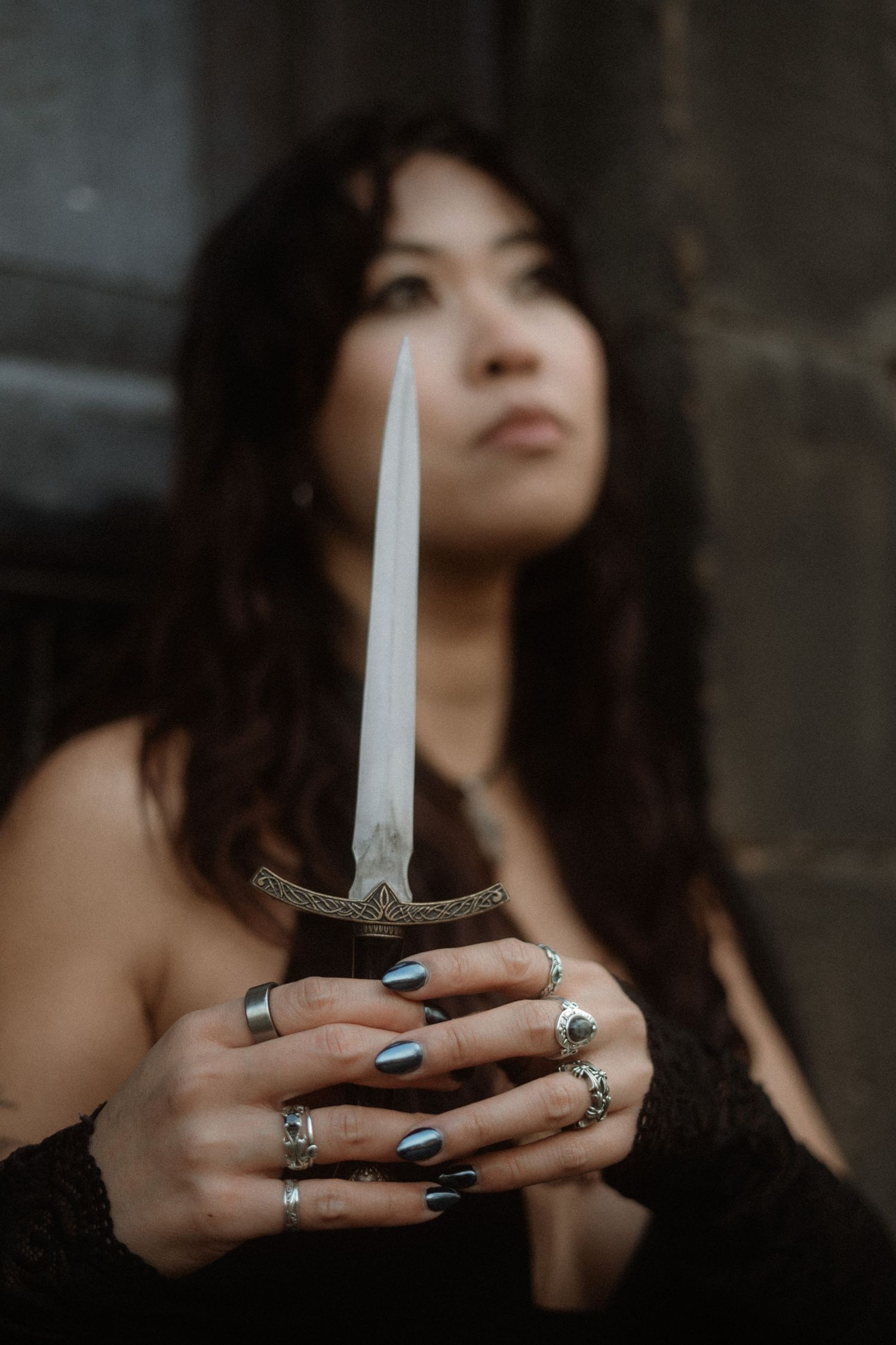 A series of moody photos showing hands with silver rings holding a white candle against a dark background.