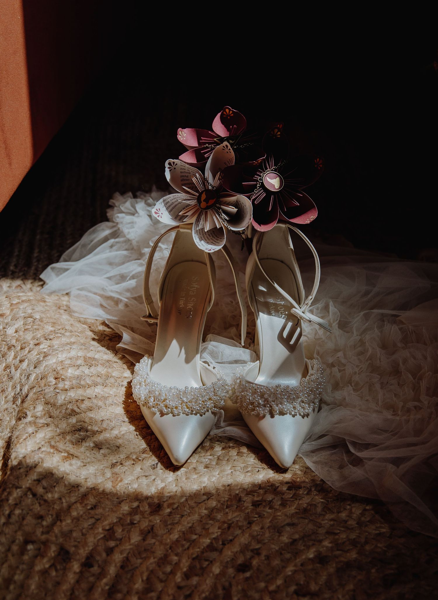 Chaussures de mariée blanches ornées de motifs floraux, photographiées sur un tissu texturé sur un Mariage à Toulouse
