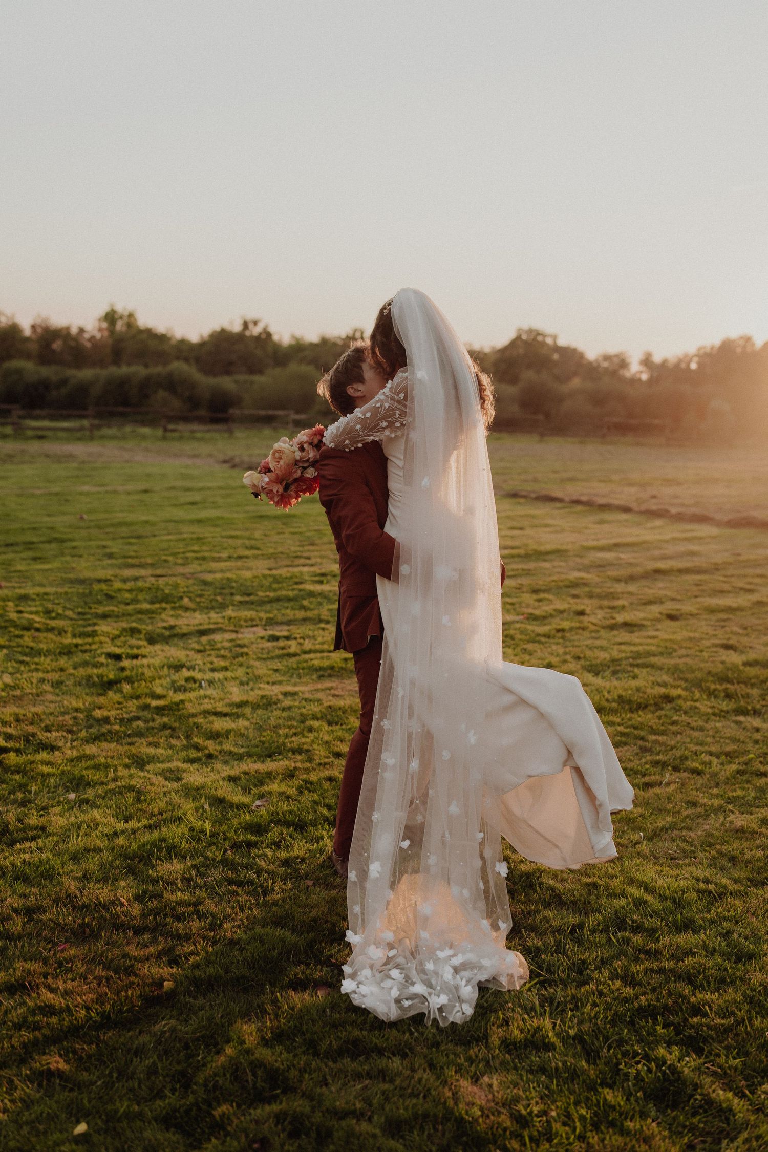 Mariés enlacés au couché du soleil dans un champ lors d'un mariage au chateau du vignau