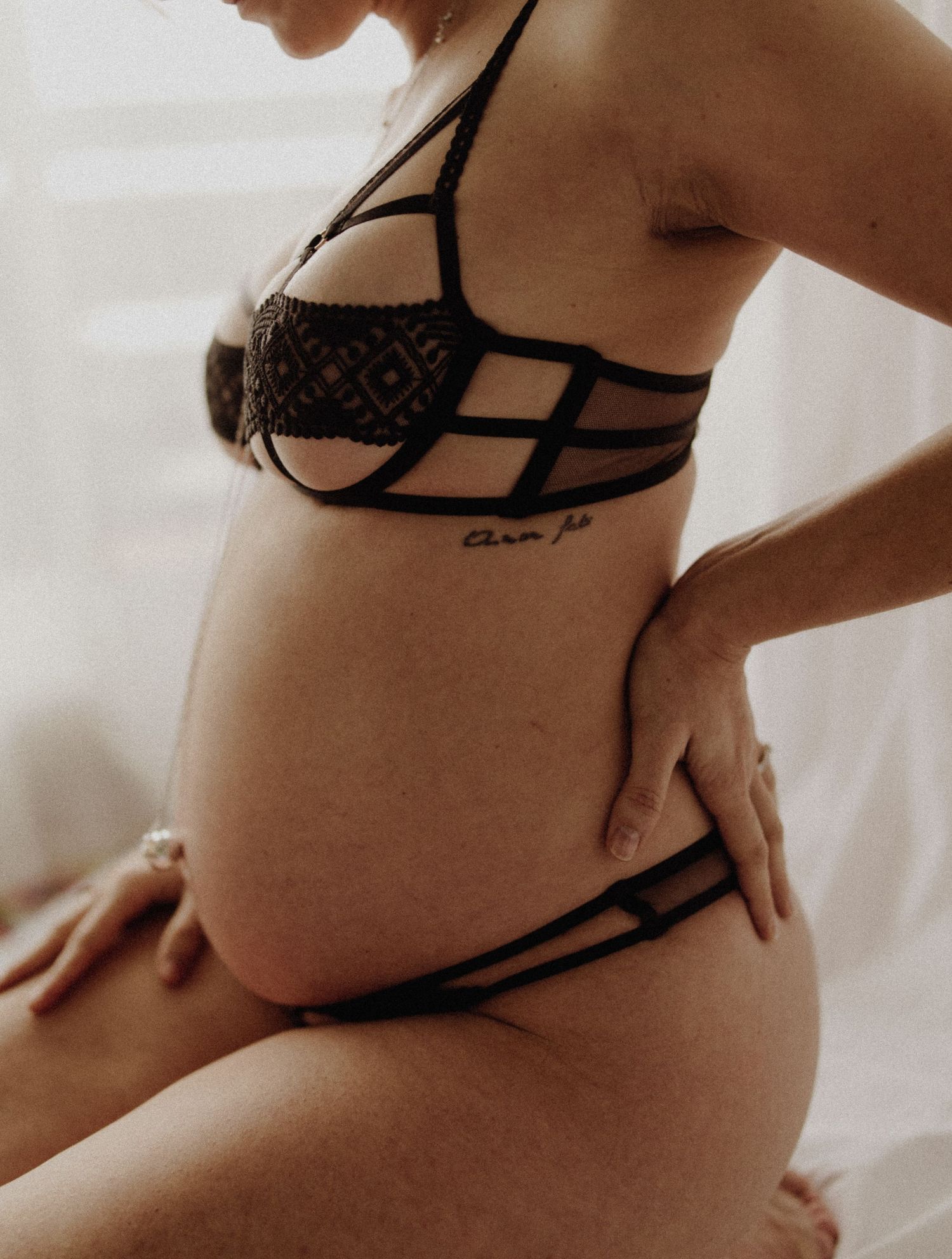 Gros plan artistique en noir et blanc d'une femme enceinte portant de la lingerie noire sur fond clair en studio à biscarrosse plage