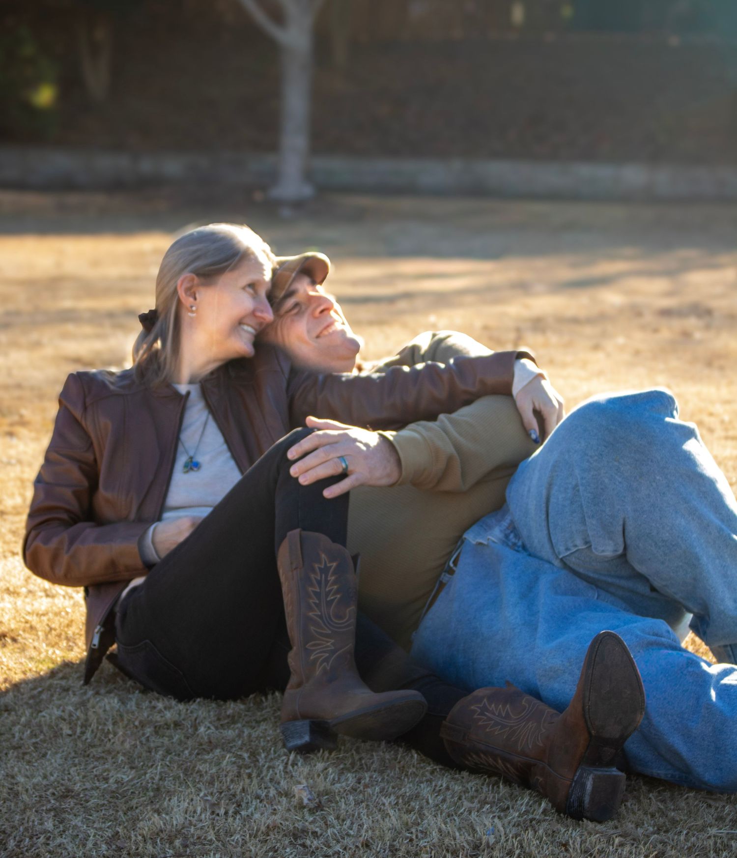 This is a photo of the grandparents cuddling in the grass, admiring their playing grandkids.