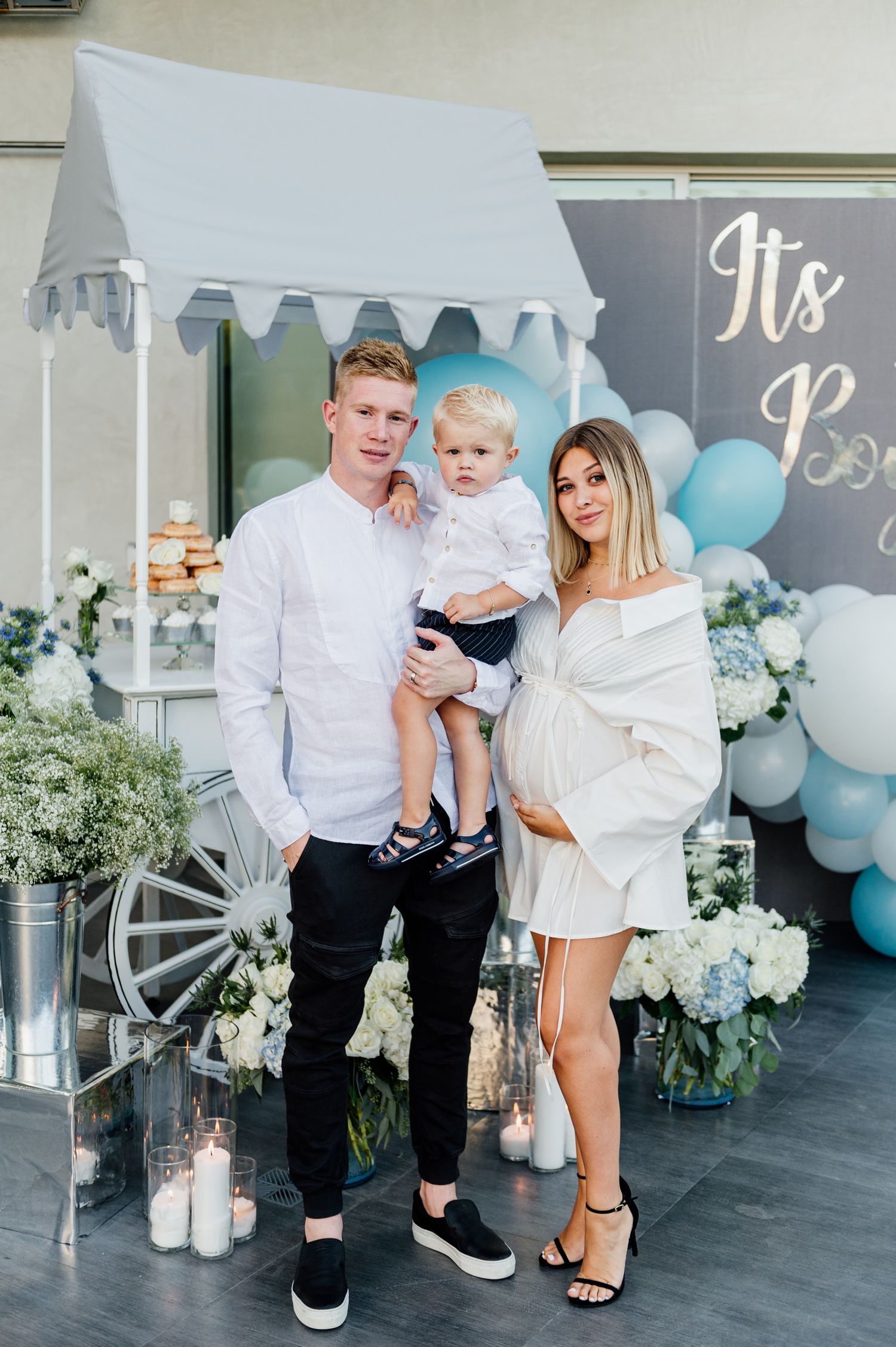 A family photo session with blue and white balloon decorations and floral arrangements.