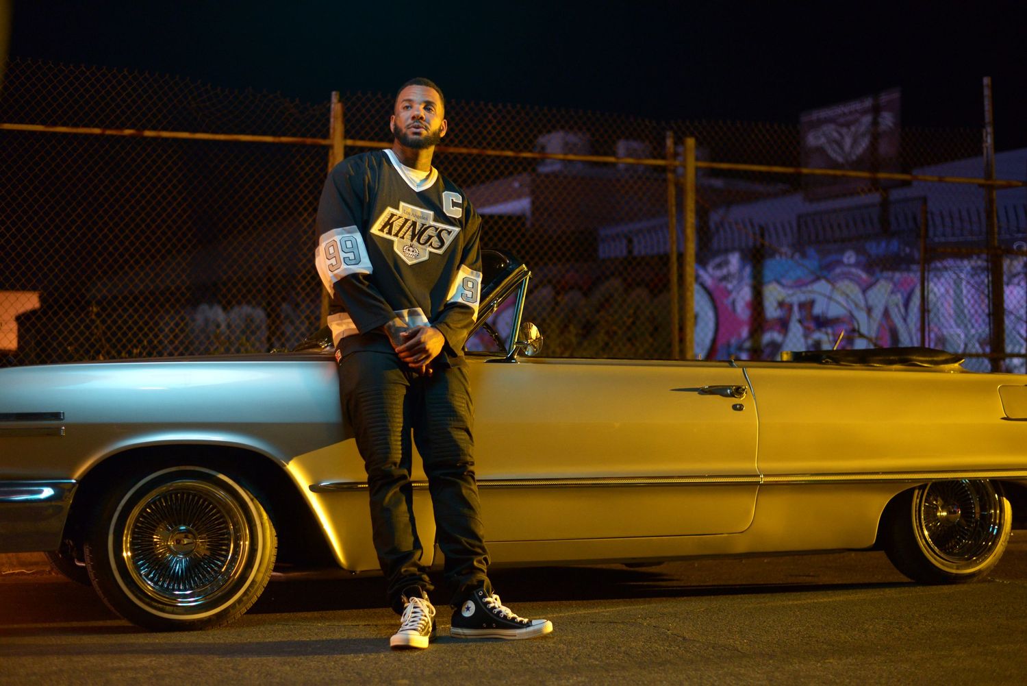 Urban nighttime portrait with vintage car and street lighting creating moody atmosphere.