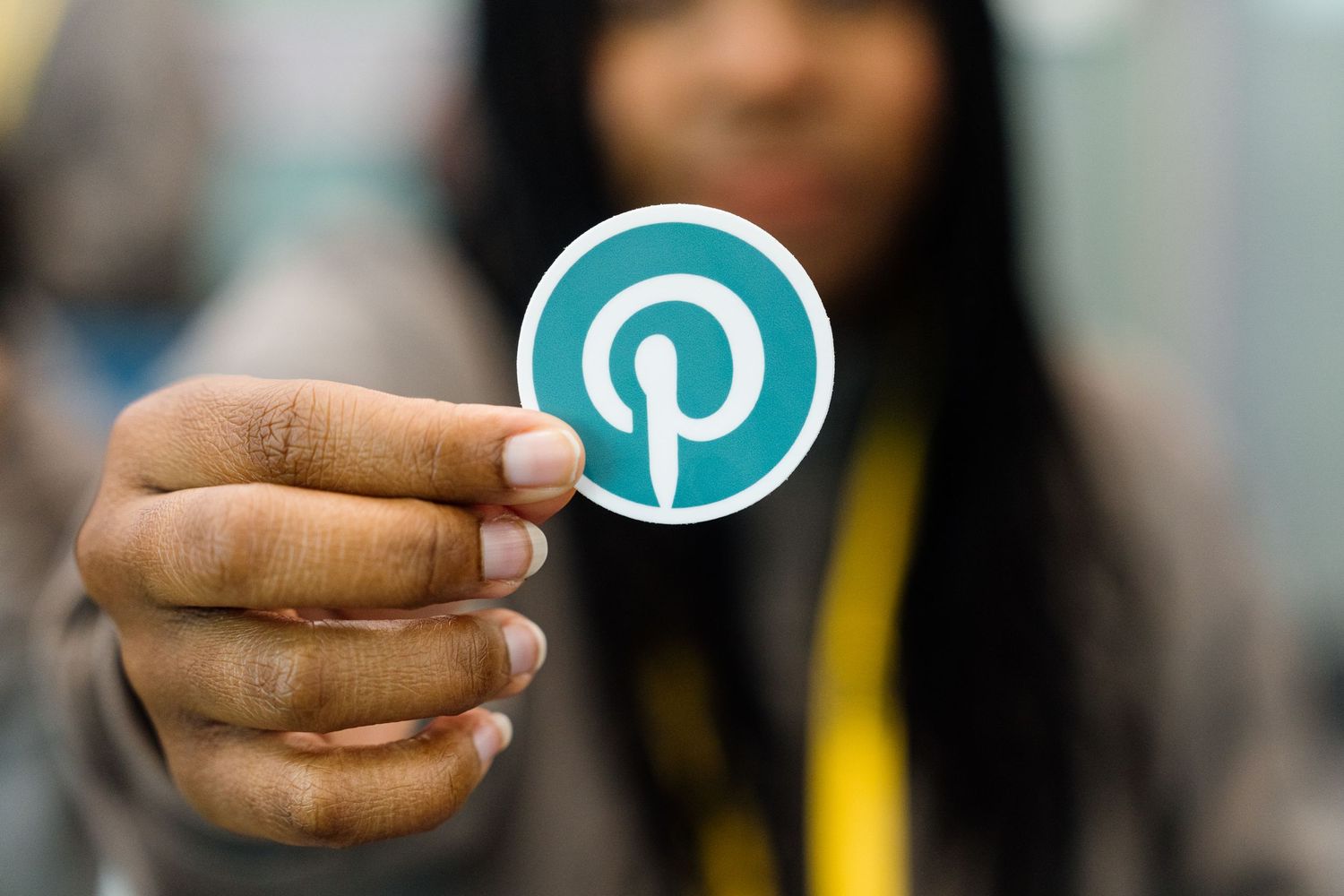 Close-up of hands holding a teal Pinterest logo symbol.