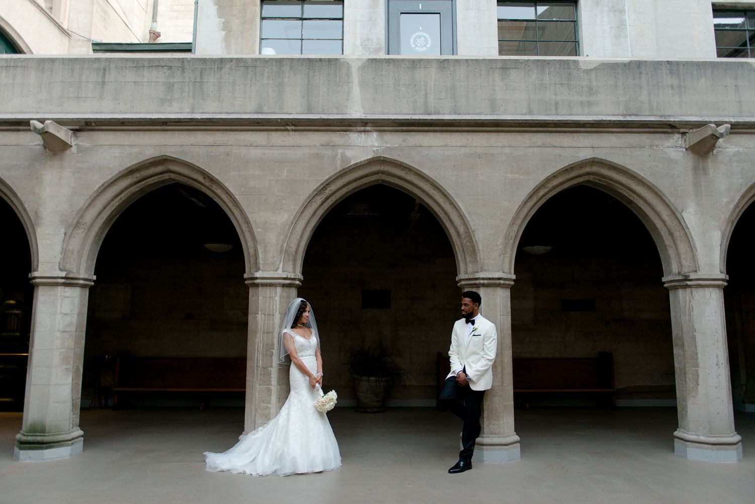 Elegant architectural wedding photos taken under stone arches and columns.