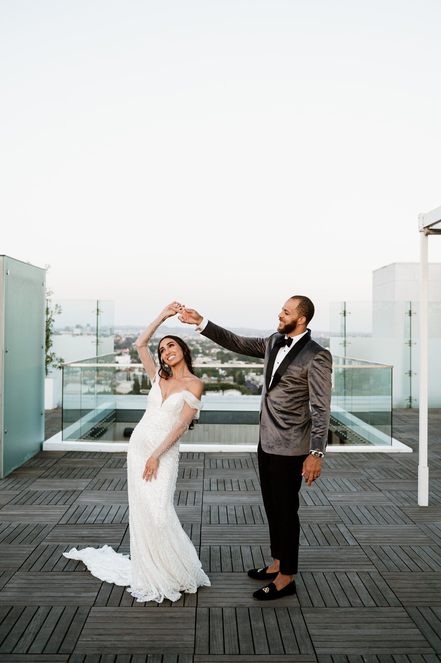 Artistic black and white wedding photos showing playful poses on a wooden deck with glass railings.