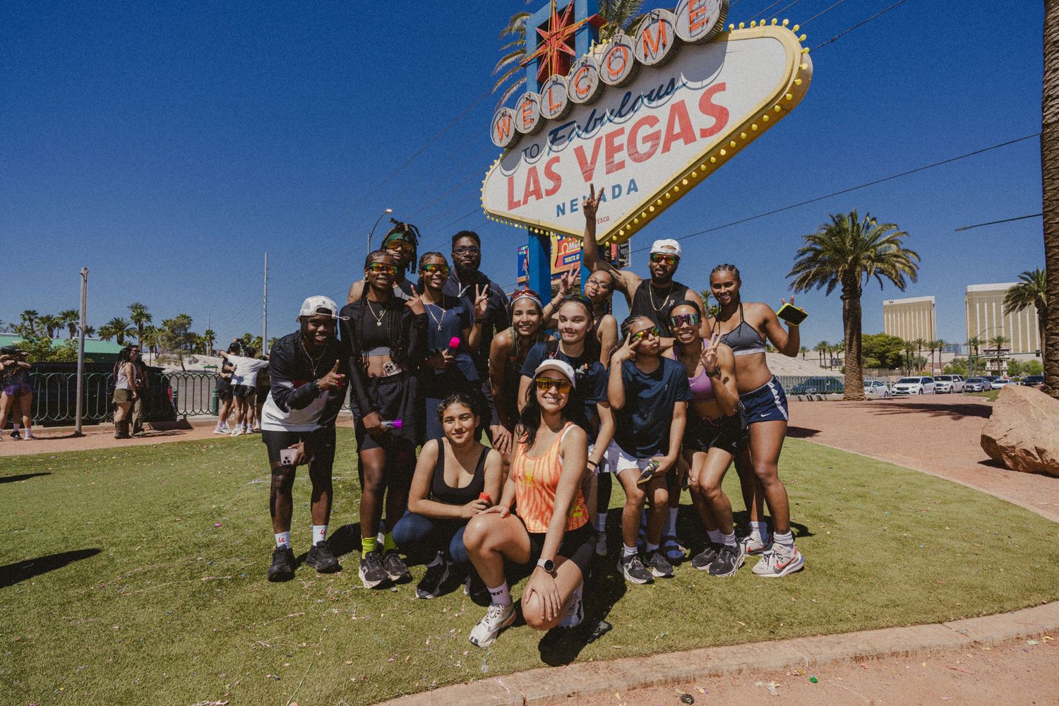Group of friends posing in front of the iconic Welcome to Fabulous Las Vegas sign on a sunny day.